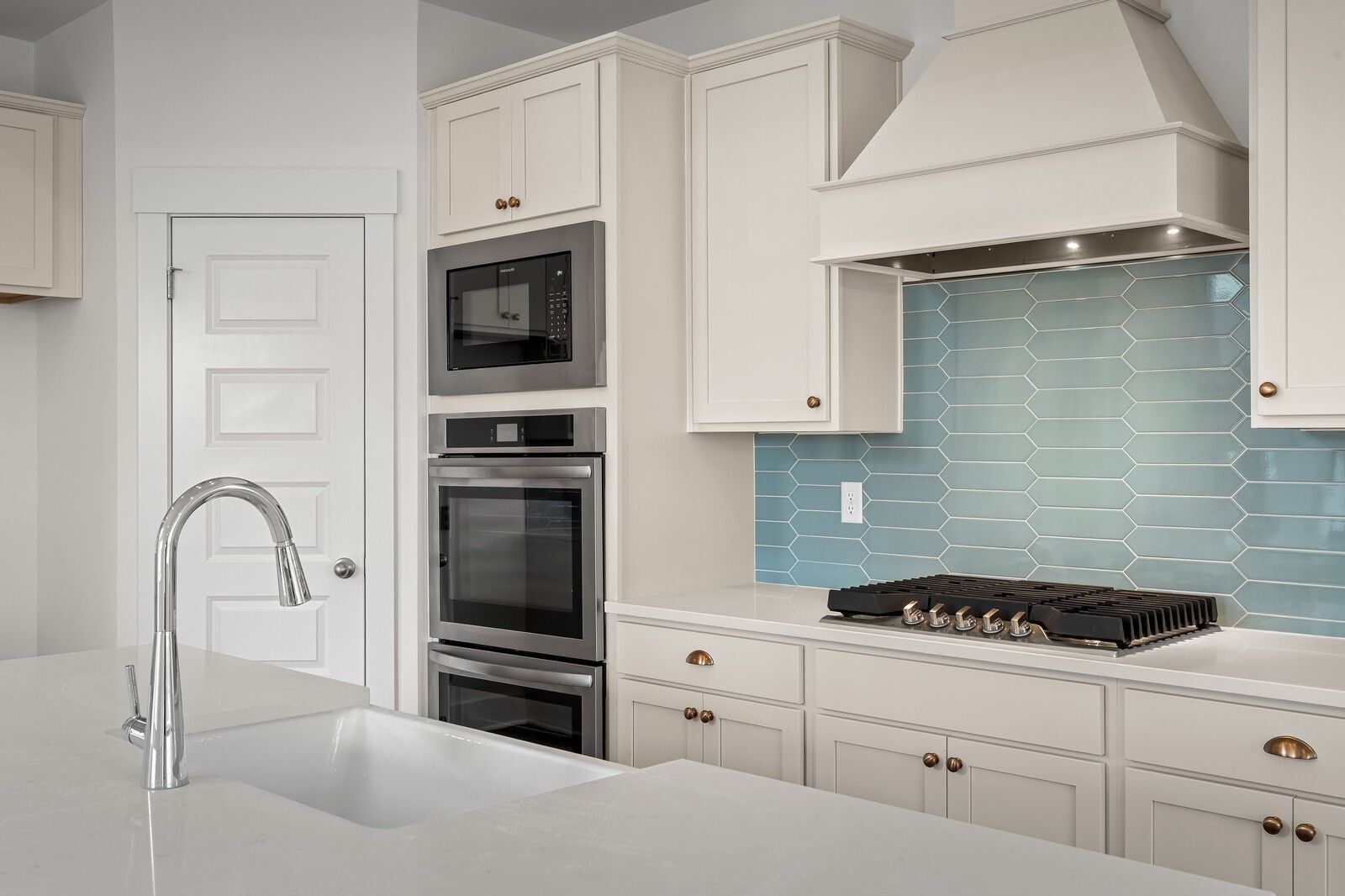 Contemporary kitchen with white cabinets, teal hex tile backsplash, stainless double oven, gas range in Davidson Homes The Ridgeport, Gallatin, TN