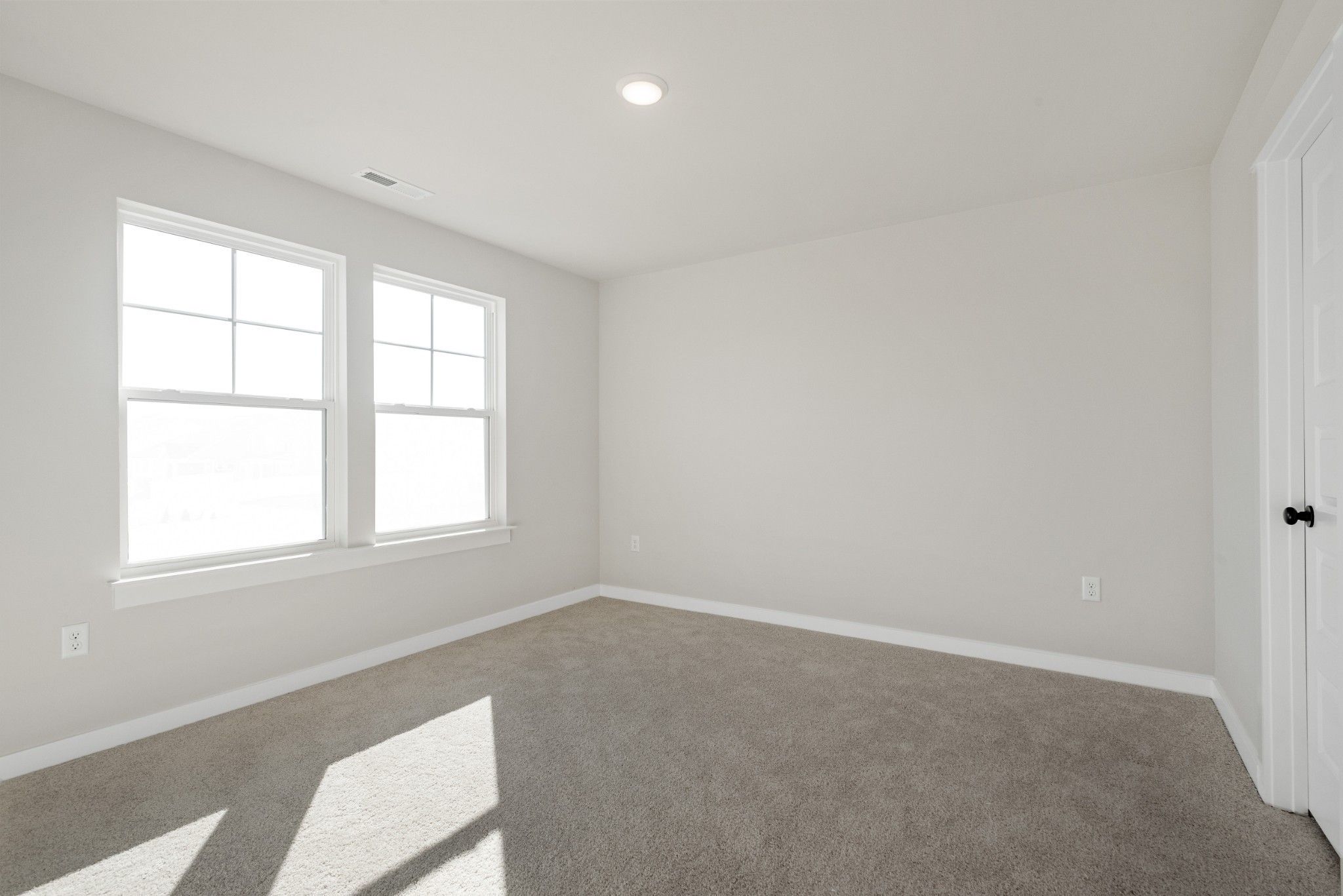 Bright, carpeted bedroom with neutral walls in The Willow B floor plan at Calista Farms in White House, Tennessee.