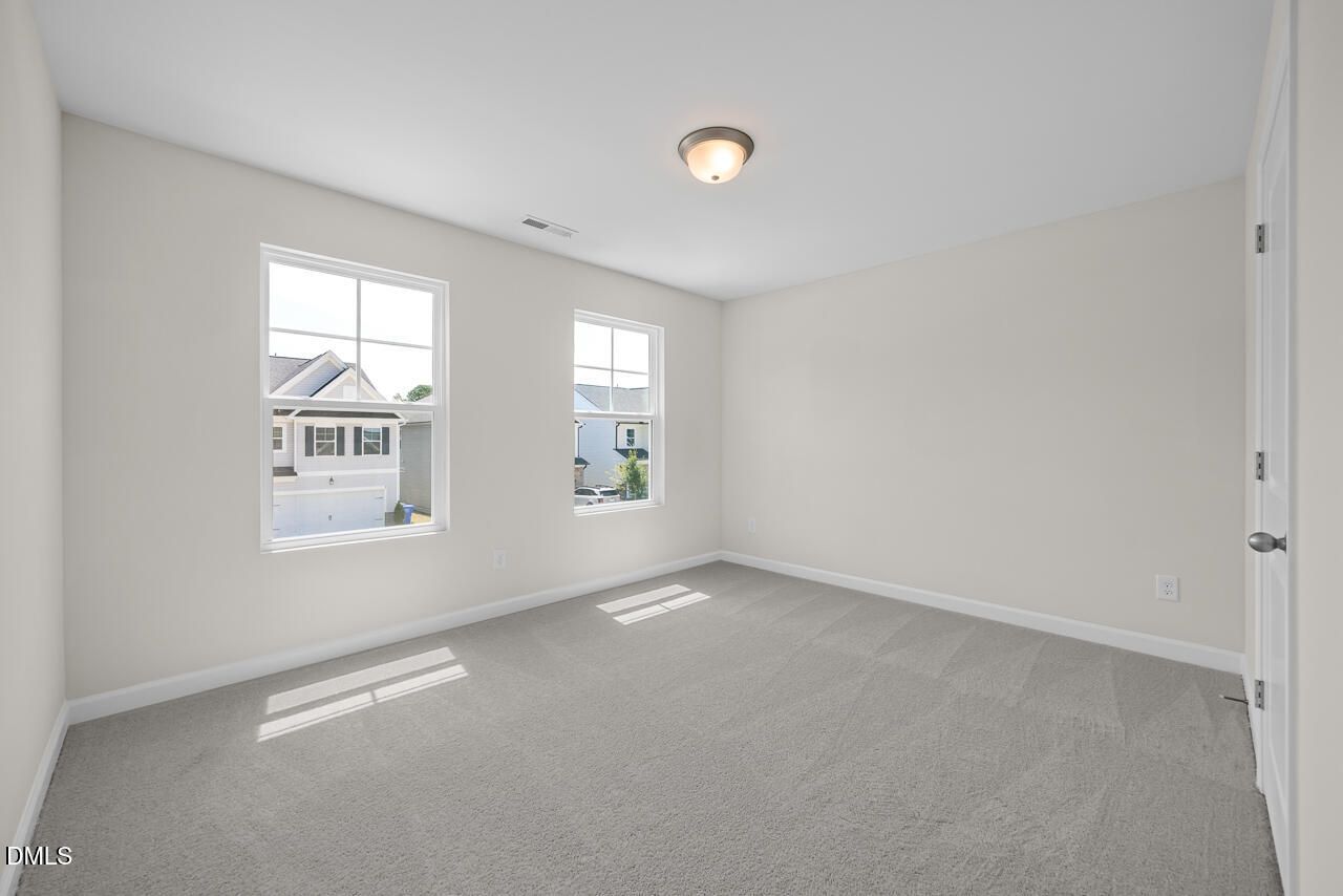 Bright, carpeted bedroom with neutral walls in The Gavin A floor plan by Davidson Homes in Gregory Village, Lillington, NC.