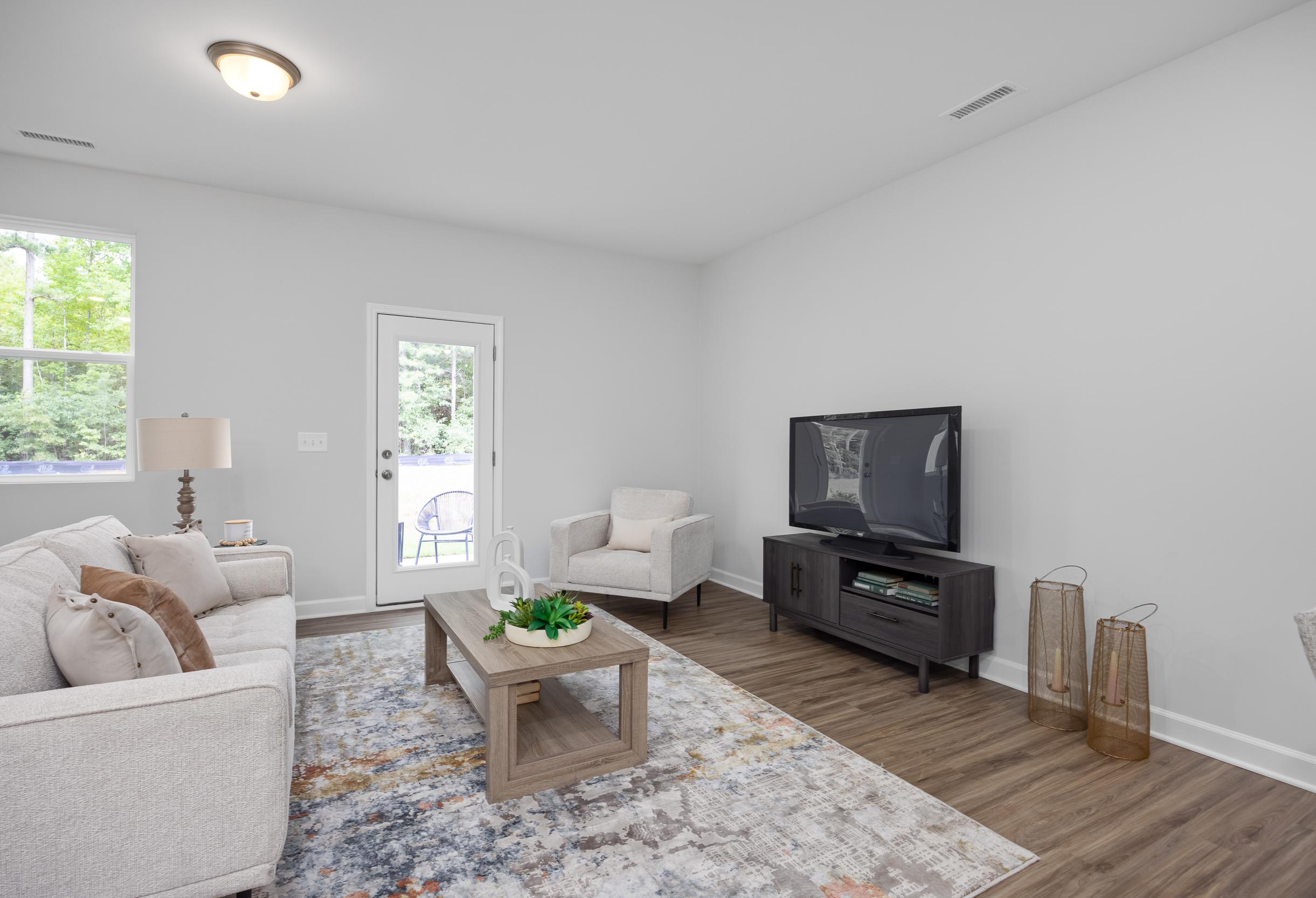 Bright living room in The Warren floor plan featuring modern furniture, wood-style flooring, and a glass door to the patio.