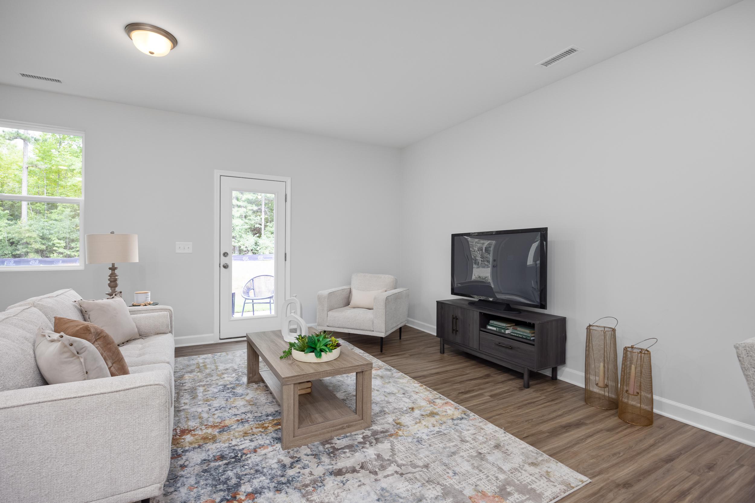Bright living room in The Warren floor plan featuring modern furniture, wood-style flooring, and a glass door to the patio.