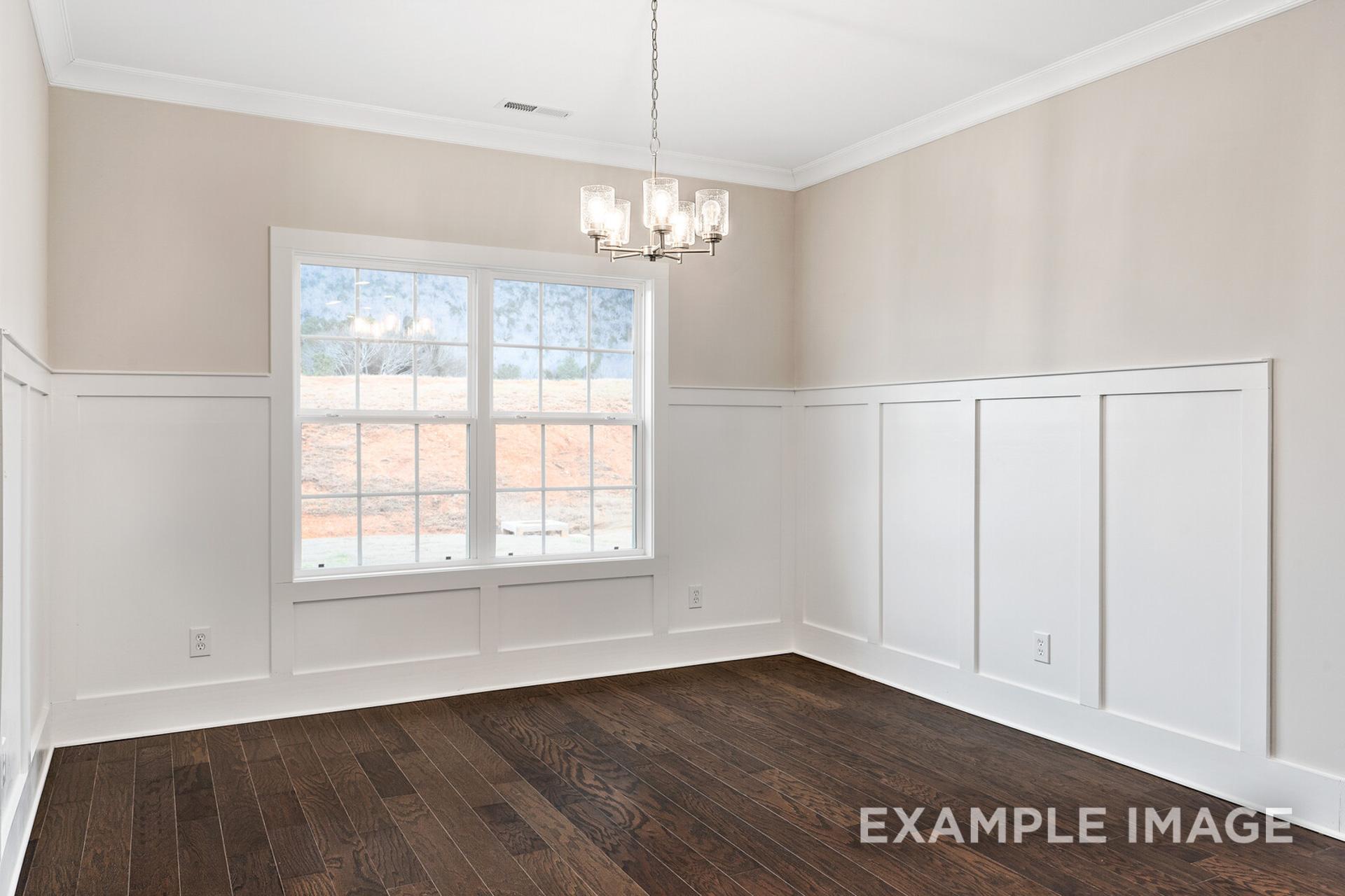 Bright dining room in The Rockford floor plan featuring white wainscoting, crystal chandelier, large windows, and hardwood floors