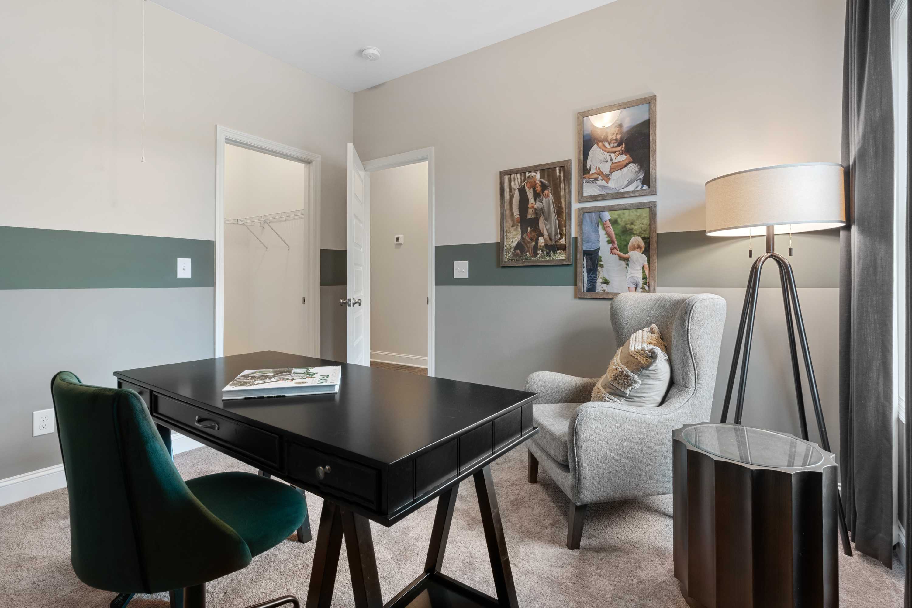 Cozy home office at The Retreat at Cain Park in Hartselle Alabama with black desk green chair armchair lamp and framed photos