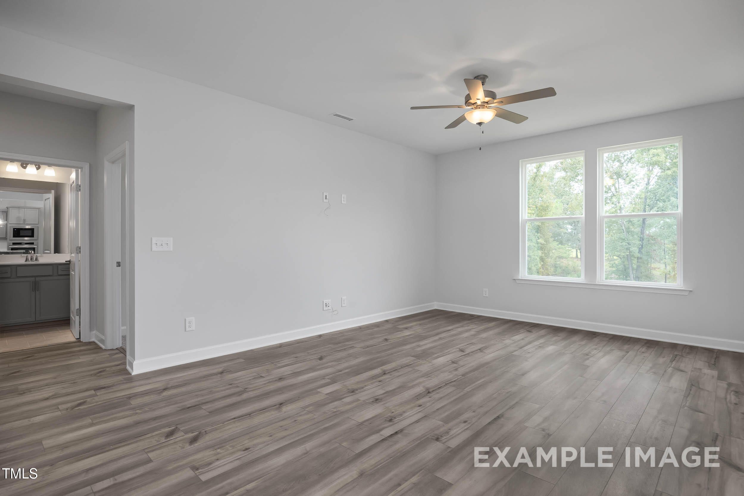 Bright bedroom with ceiling fan, luxury vinyl plank floors, large windows, and en-suite bath in The Willow E, Davidson Homes, Angier NC