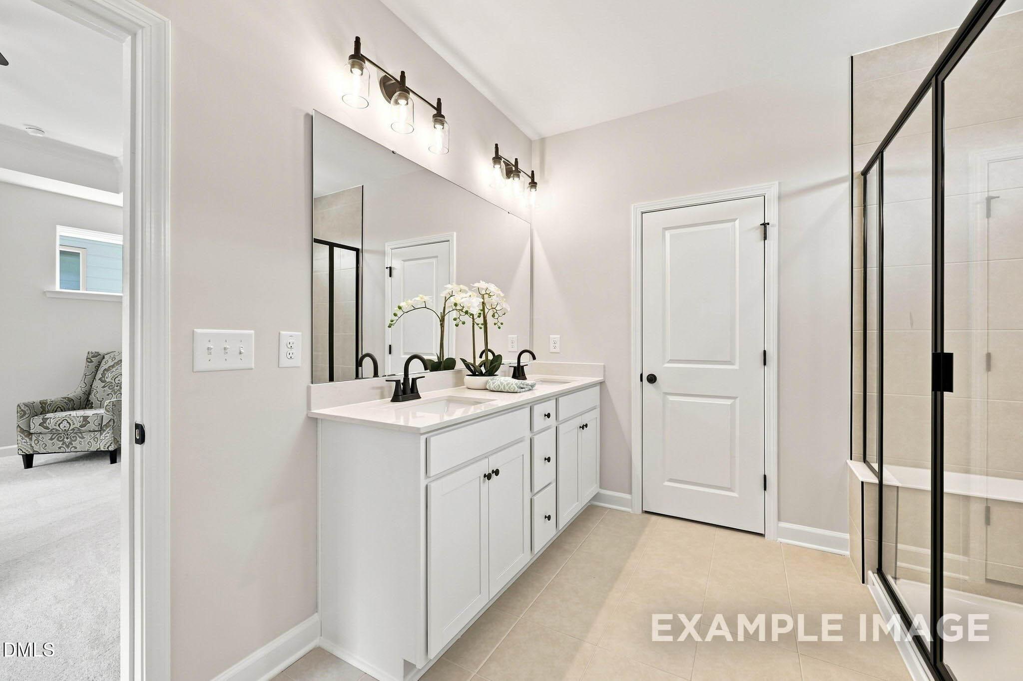 Primary bathroom with double vanity, black fixtures, and frameless glass shower in Davidson Homes The Harris A, Knightdale, NC