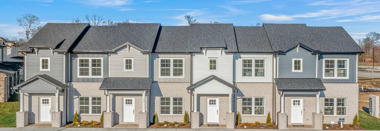 Row of modern gray townhomes with white doors and landscaping at The Towns at Red River in Gallatin, Tennessee