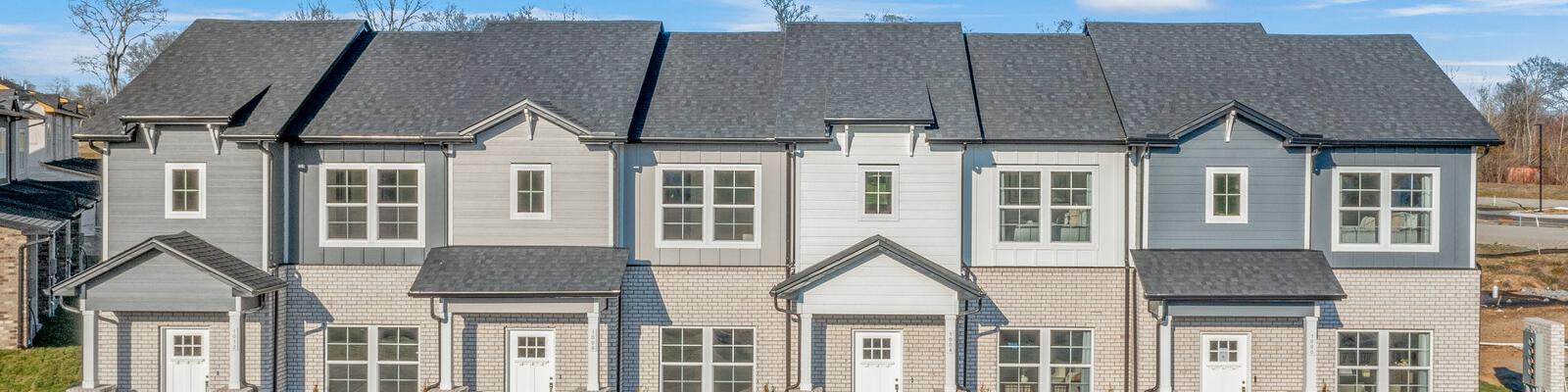 Row of modern gray townhomes with white doors and landscaping at The Towns at Red River in Gallatin, Tennessee