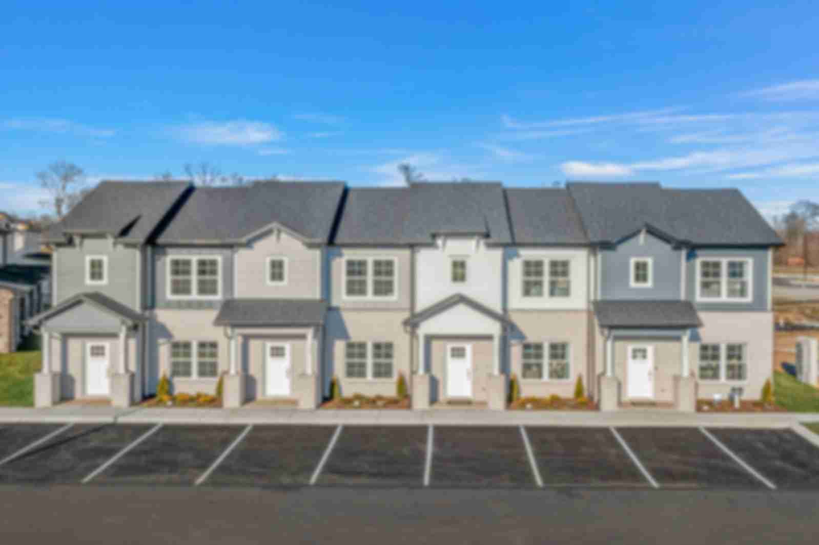 Row of modern gray townhomes with white doors and landscaping at The Towns at Red River in Gallatin, Tennessee
