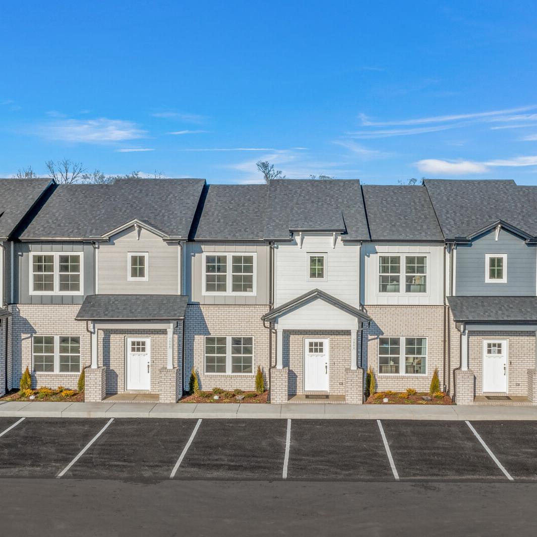 Row of modern gray townhomes with white doors and landscaping at The Towns at Red River in Gallatin, Tennessee