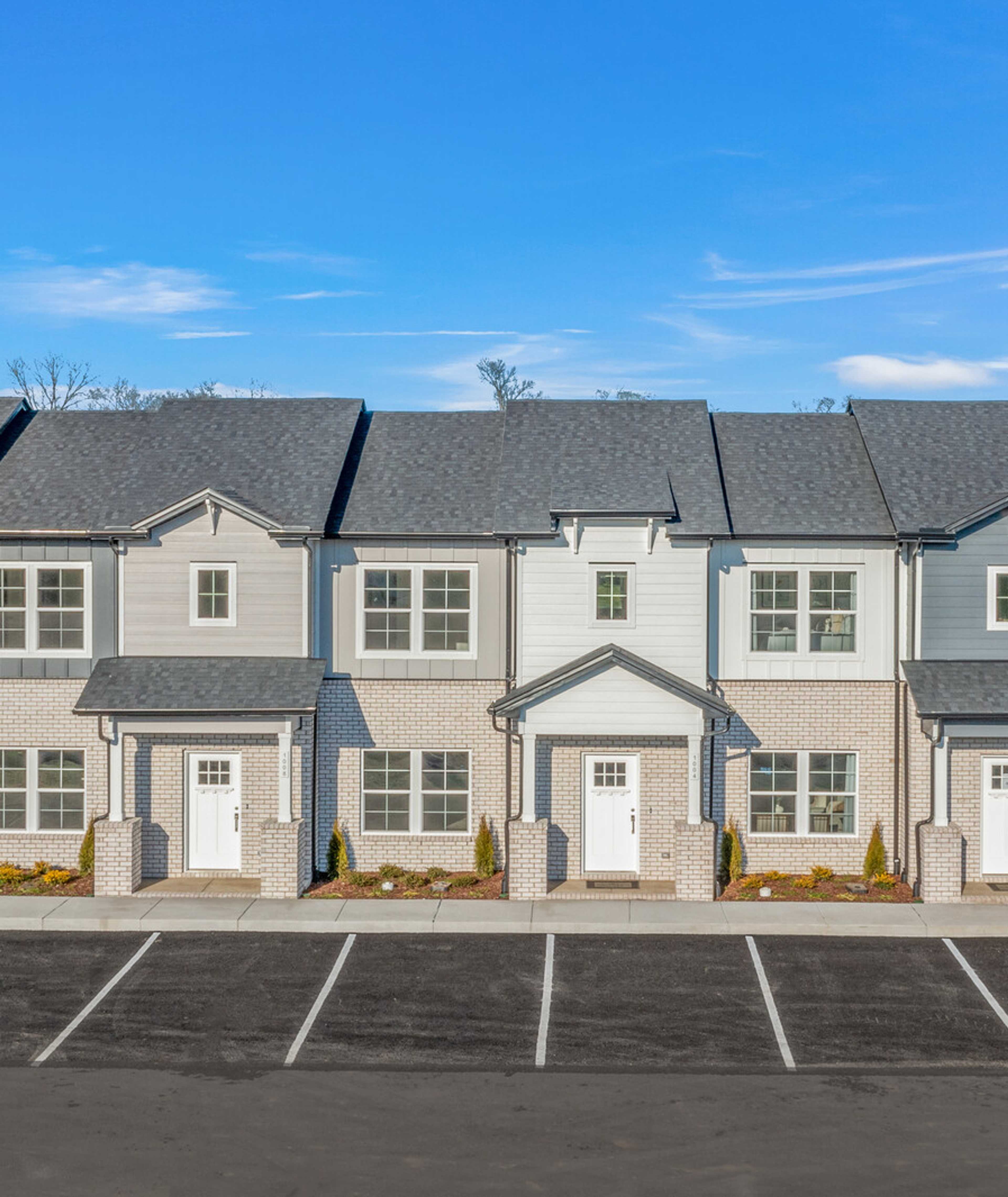 Row of modern gray townhomes with white doors and landscaping at The Towns at Red River in Gallatin, Tennessee