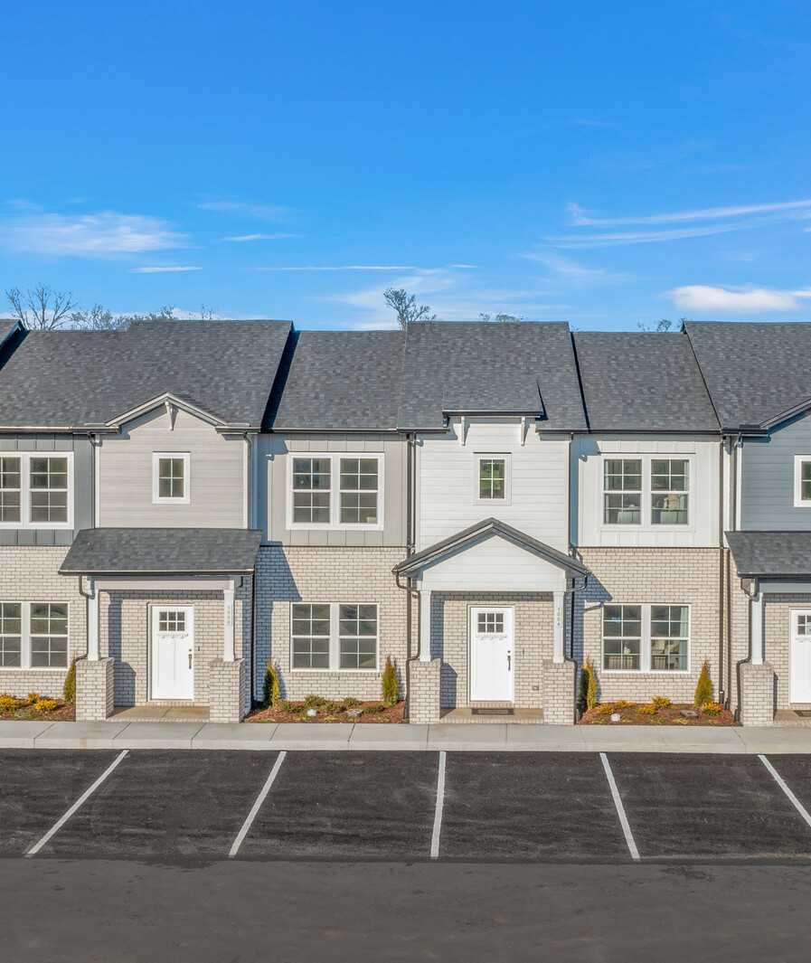 Row of modern gray townhomes with white doors and landscaping at The Towns at Red River in Gallatin, Tennessee