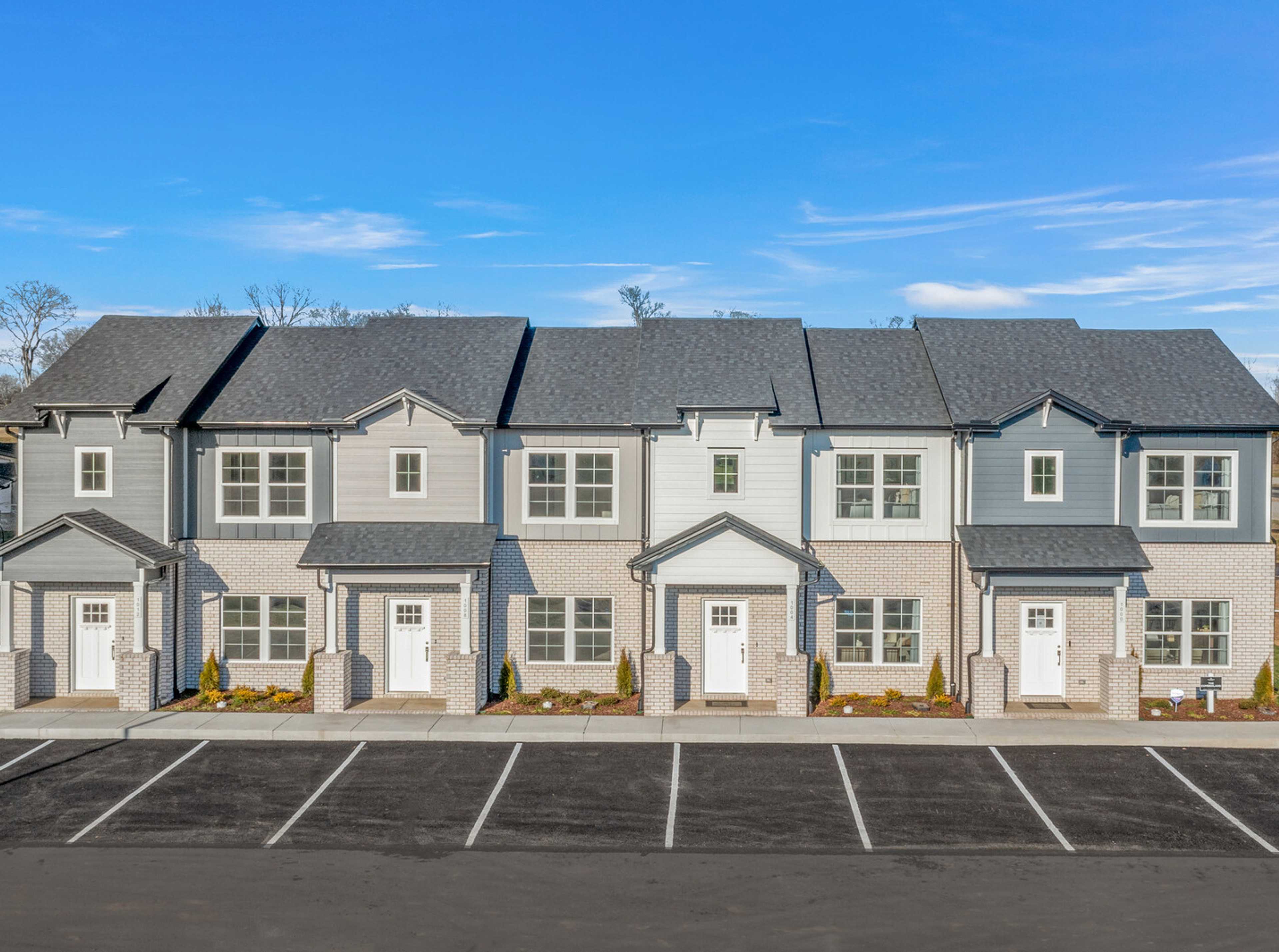 Row of modern gray townhomes with white doors and landscaping at The Towns at Red River in Gallatin, Tennessee