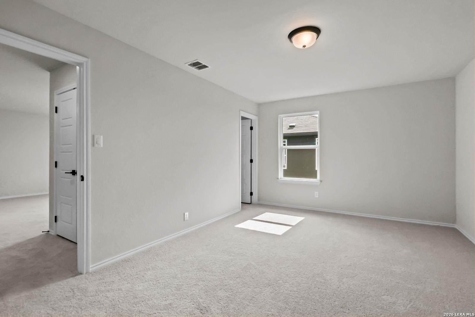 Bright, carpeted bedroom with neutral walls in The Douglas C floor plan by Davidson Homes in Hannah Heights, Seguin, Texas.