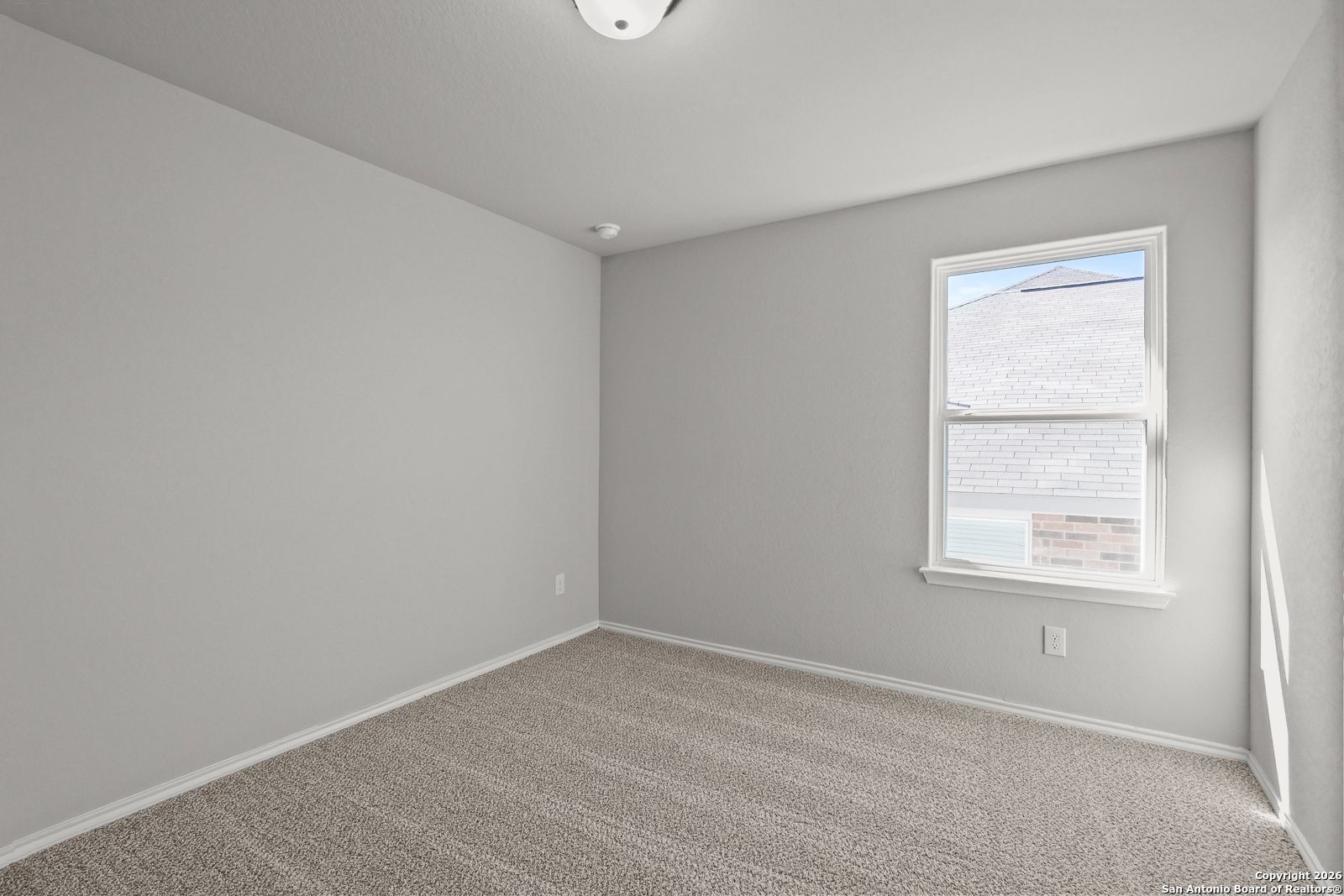 Bright secondary bedroom with gray walls, beige carpet, large window, and neutral tones in Davidson Homes The Murray K, San Antonio