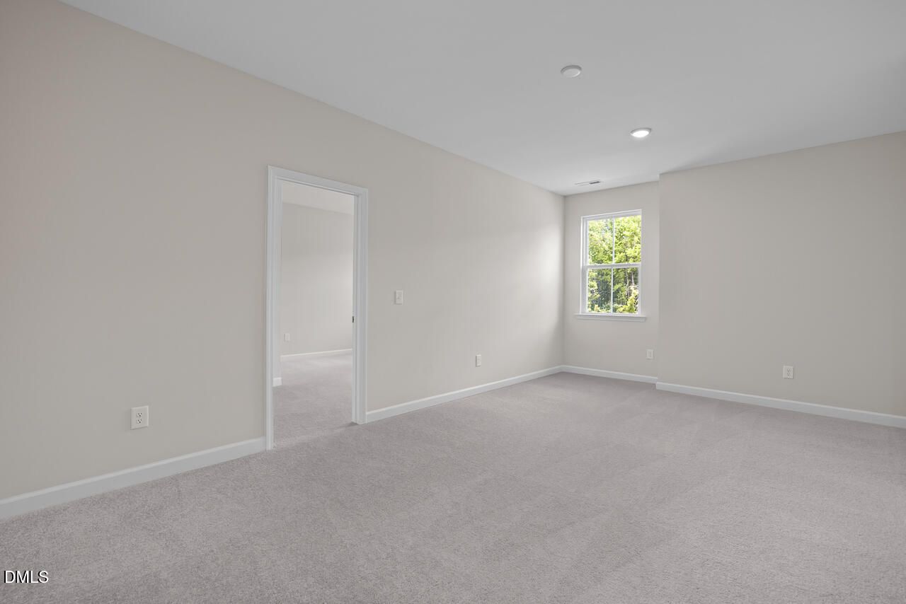 Spacious carpeted bedroom with neutral walls in The Ashport G floor plan at Sage on North Main in Wake Forest, NC.