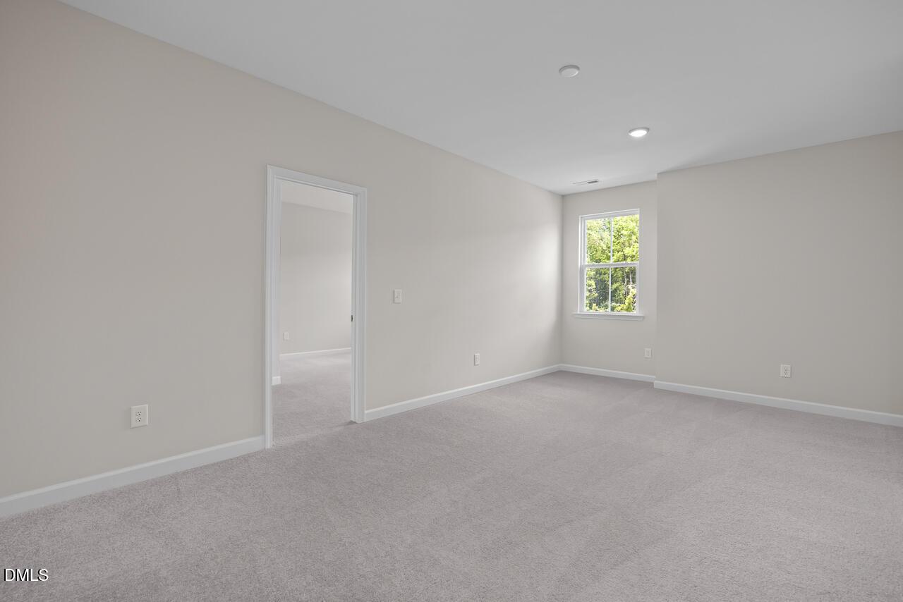 Spacious carpeted bedroom with neutral walls in The Ashport G floor plan at Sage on North Main in Wake Forest, NC.