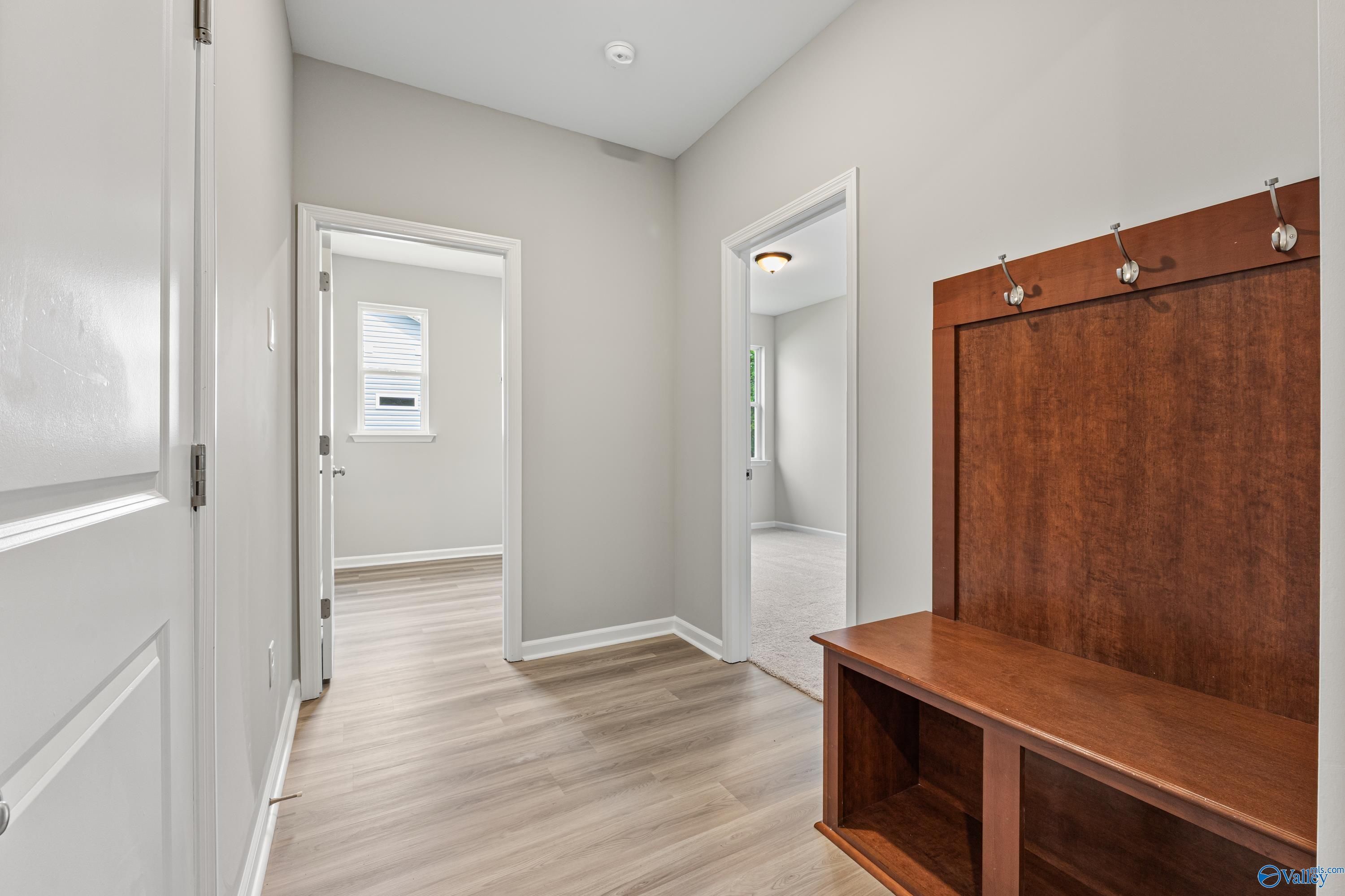 Bright entryway hallway with gray walls, wooden bench, coat hooks, and laminate flooring in Davidson Homes The Aurora, Fayetteville