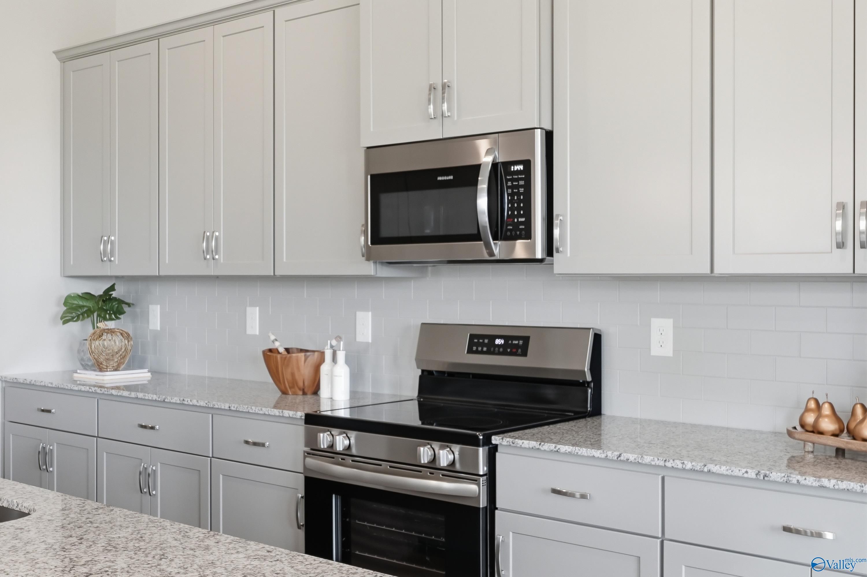 Modern gray shaker kitchen with quartz countertops, stainless steel appliances, subway tile backsplash in Davidson Homes The Arcadia B, Huntsville AL