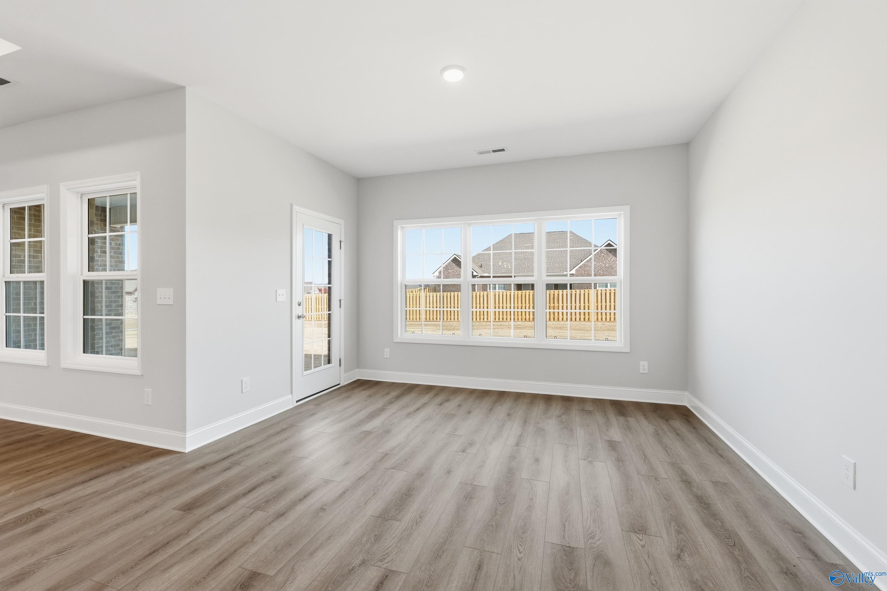 Spacious living room with hardwood floors and large windows to fenced backyard in Davidson Homes The Finleigh, Harvest, AL