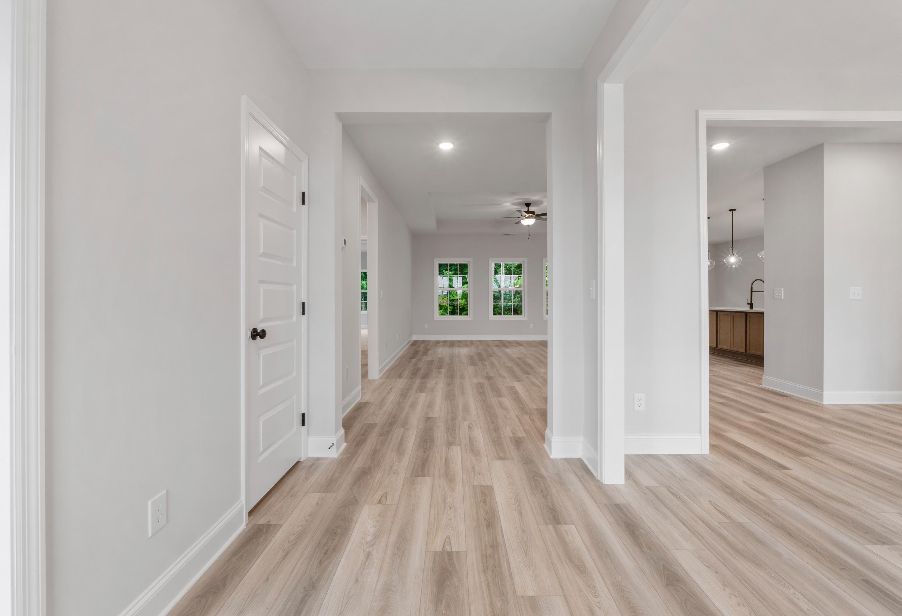 Spacious entry hallway in The Oxford home design with white doors, laminate wood floors, and open layout to living area