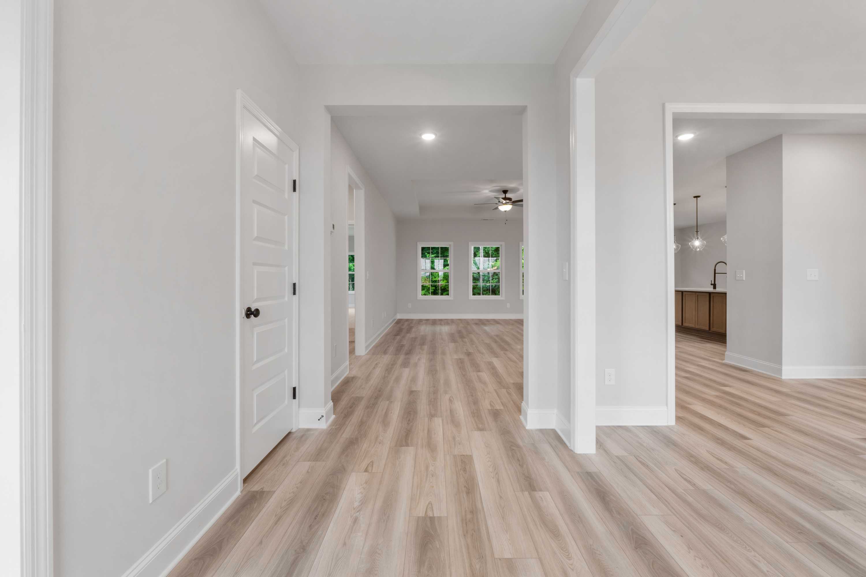 Spacious entry hallway in The Oxford home design with white doors, laminate wood floors, and open layout to living area