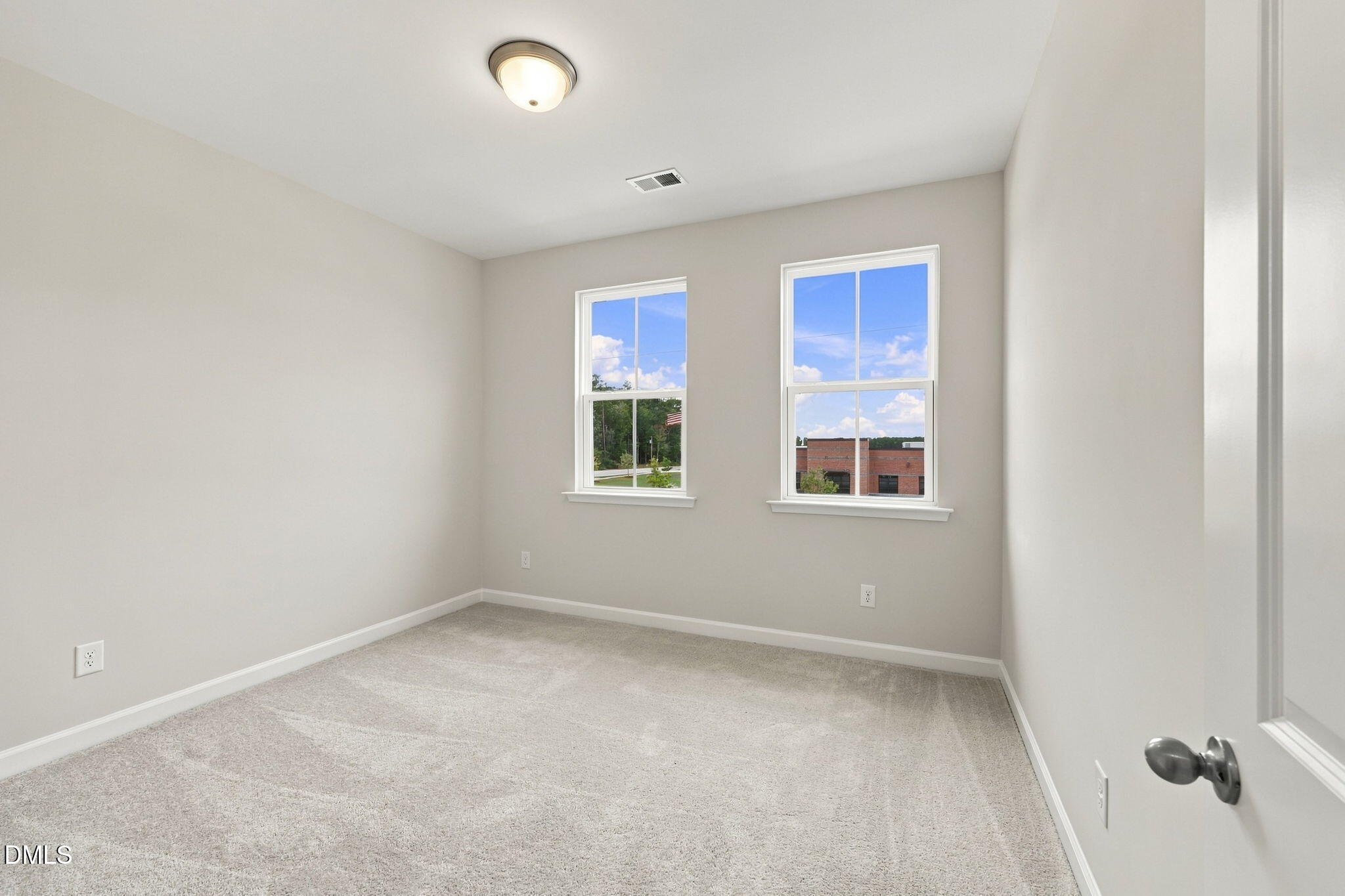 Bright empty bedroom with carpet and double windows in Davidson Homes The Alexander B, Forestville Yard, Knightdale NC