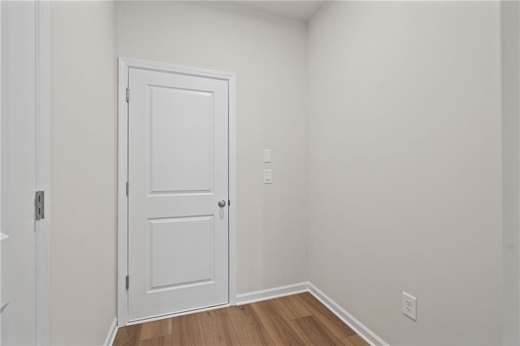 Compact powder room with white paneled door, neutral gray walls, and wood flooring in Davidson Homes The Marion B, Kennesaw, GA