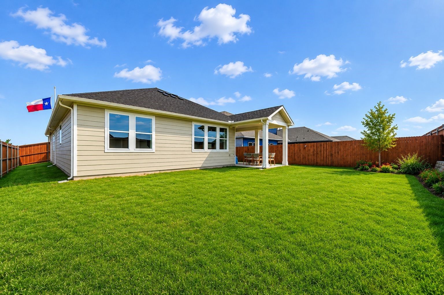 Backyard of a 1-story Davidson Homes Laurel I floor plan in Heartland, Texas, featuring a covered patio and green lawn.
