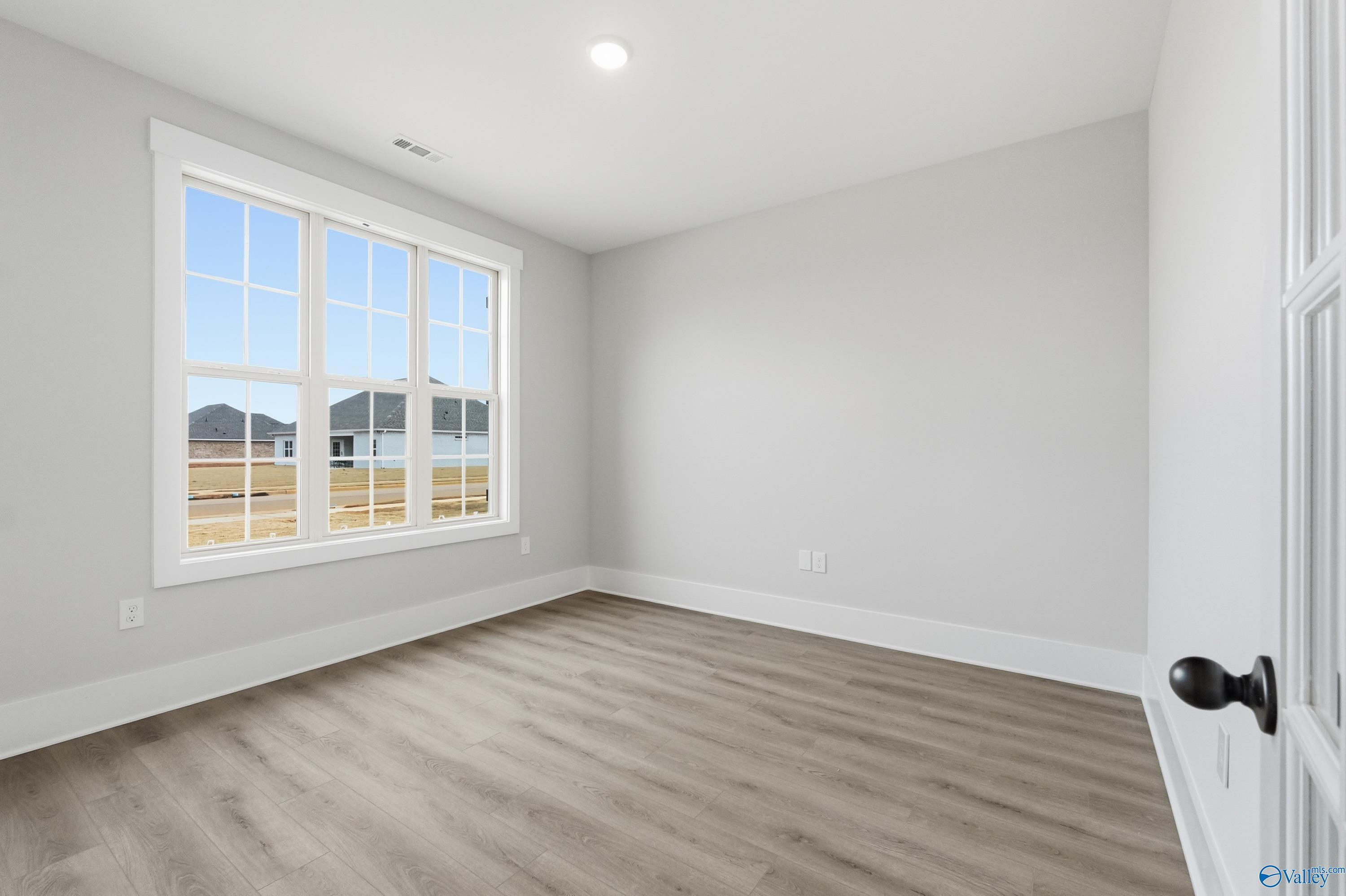 Bright secondary bedroom with hardwood floors, large windows overlooking neighborhood in Davidson Homes The Finleigh, Meridianville, Alabama