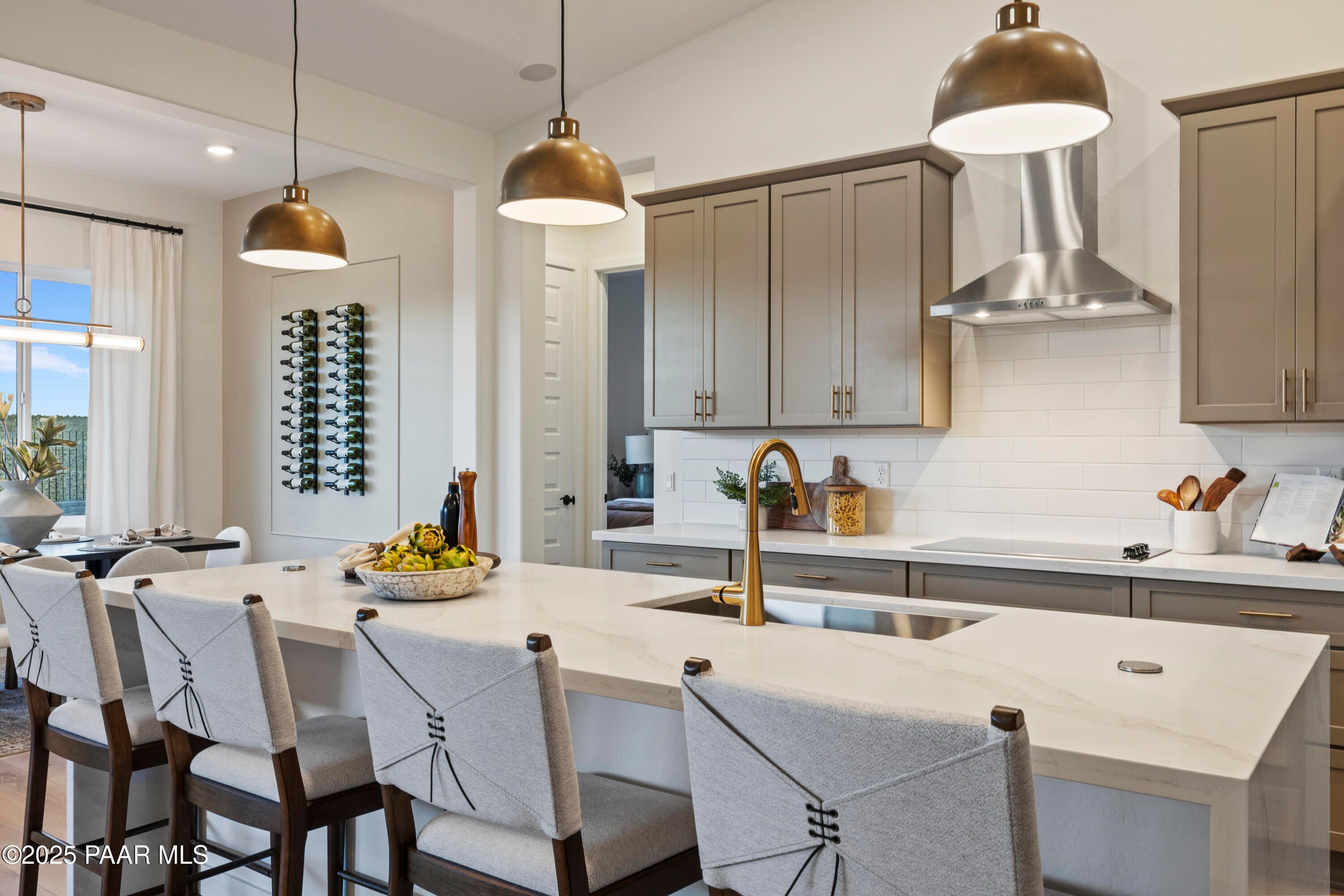 Modern kitchen island with white quartz countertop, gold faucet, subway tile backsplash in Davidson Homes The Blaze D, Prescott AZ