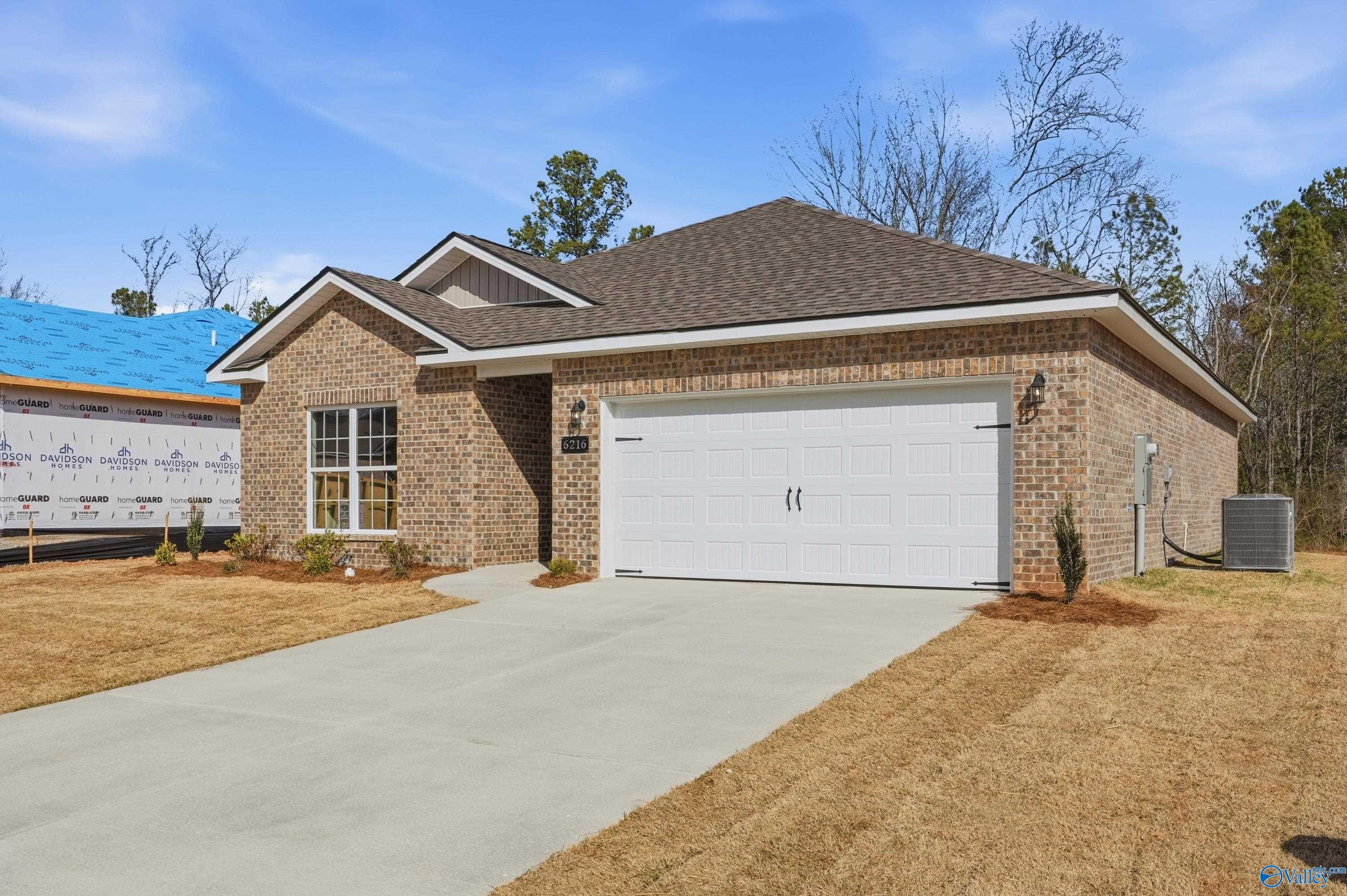 Brick ranch home with 2-car garage, concrete driveway, and pine straw landscaping in Spragins Cove, Huntsville, Alabama - The Asheville by Davidson Homes