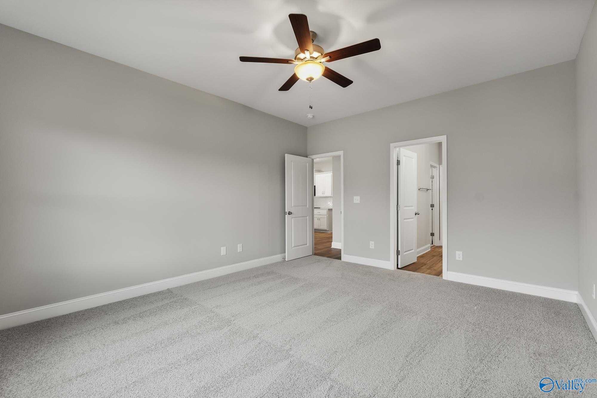 Spacious secondary bedroom with gray walls, ceiling fan, carpeted floor, and doors to bathroom in Davidson Homes The Daphne D, Athens, AL