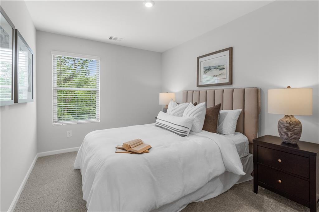 Serene bedroom with beige upholstered headboard, white linens, decorative pillows, and bedside lamps in Davidson Homes The Durant A, Emerson, Georgia