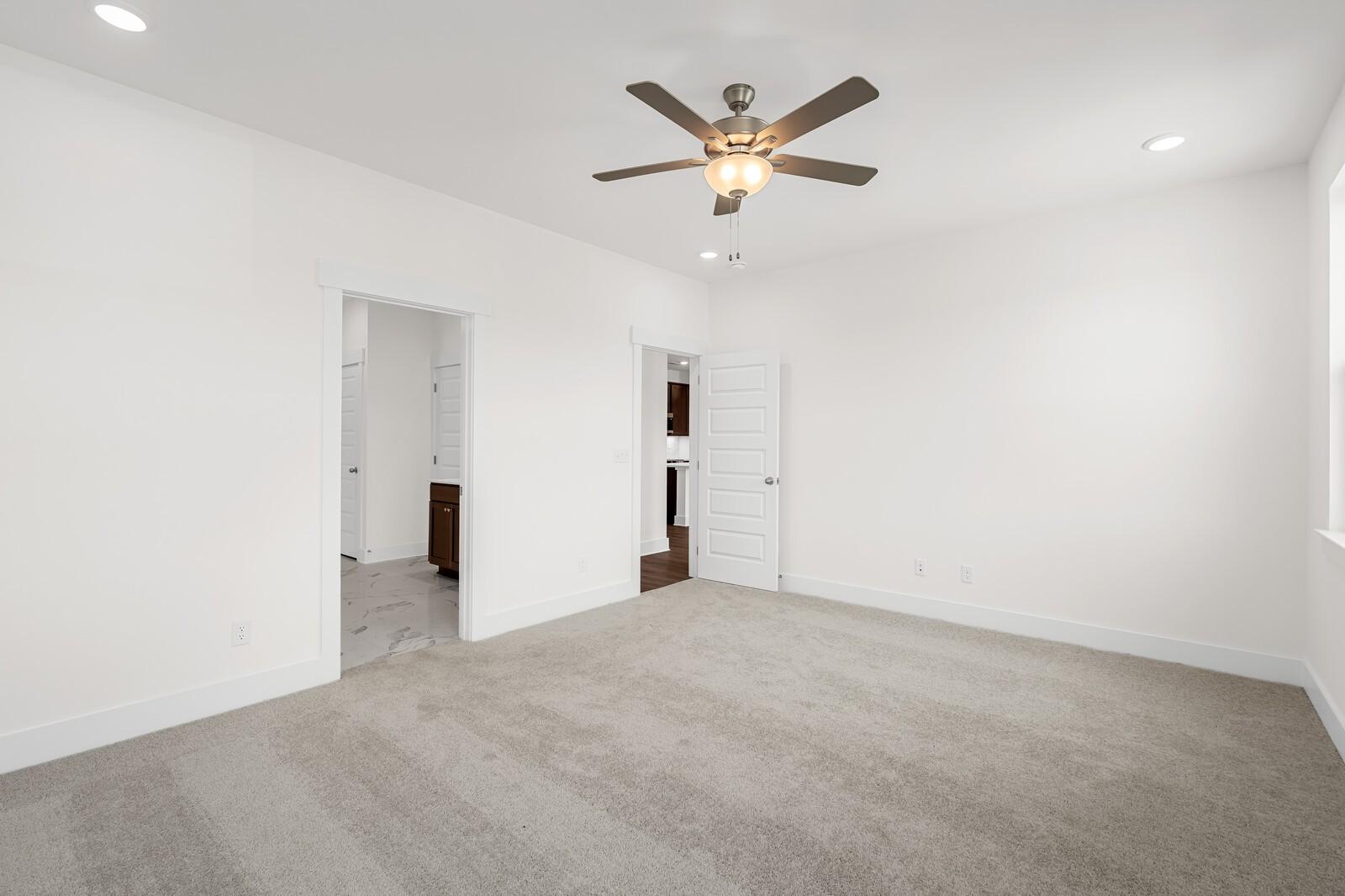 Bright bedroom with plush carpet and ceiling fan in The Cottonwood E floor plan at Woods Crossing, Gallatin, Tennessee.