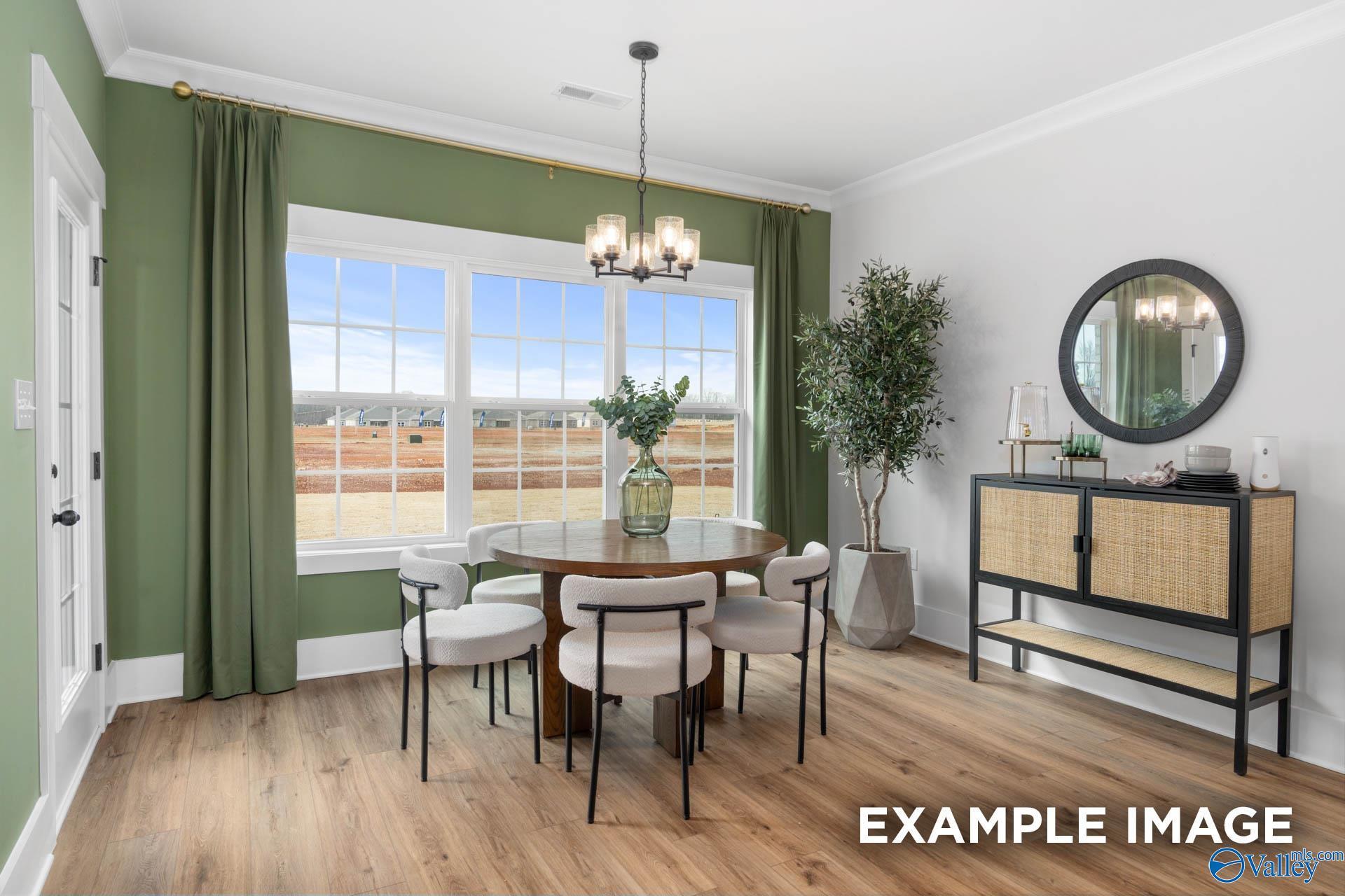 Elegant dining room featuring round wood table, white chairs, green curtains, and large windows in The Finleigh 5-bedroom home, Decatur, Alabama