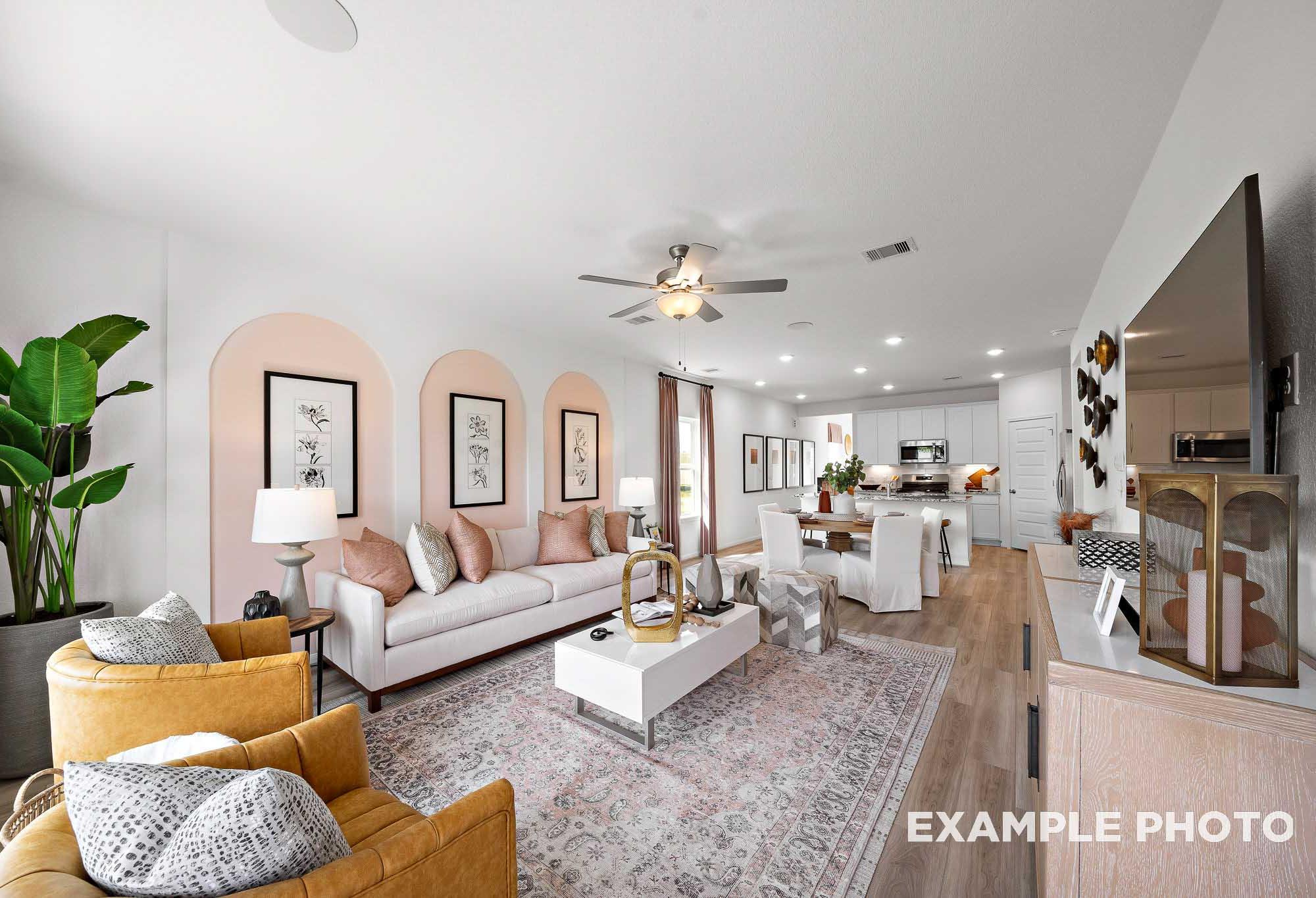 Spacious open-concept living and dining in The Sabine F home featuring white sofa, pink arched walls, potted plants, and modern kitchen