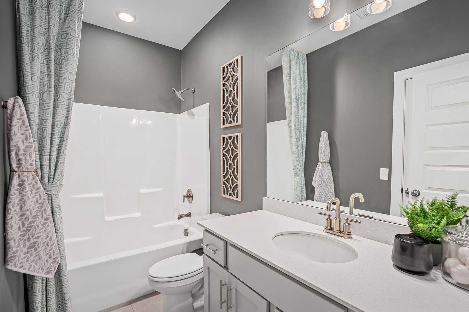 Modern bathroom at Sage Farms in White House TN by Davidson Homes with gray walls, white tub-shower combo, and vanity