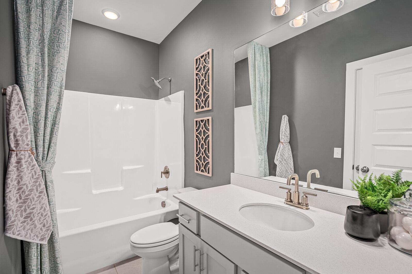 Modern bathroom at Sage Farms in White House TN by Davidson Homes with gray walls, white tub-shower combo, and vanity