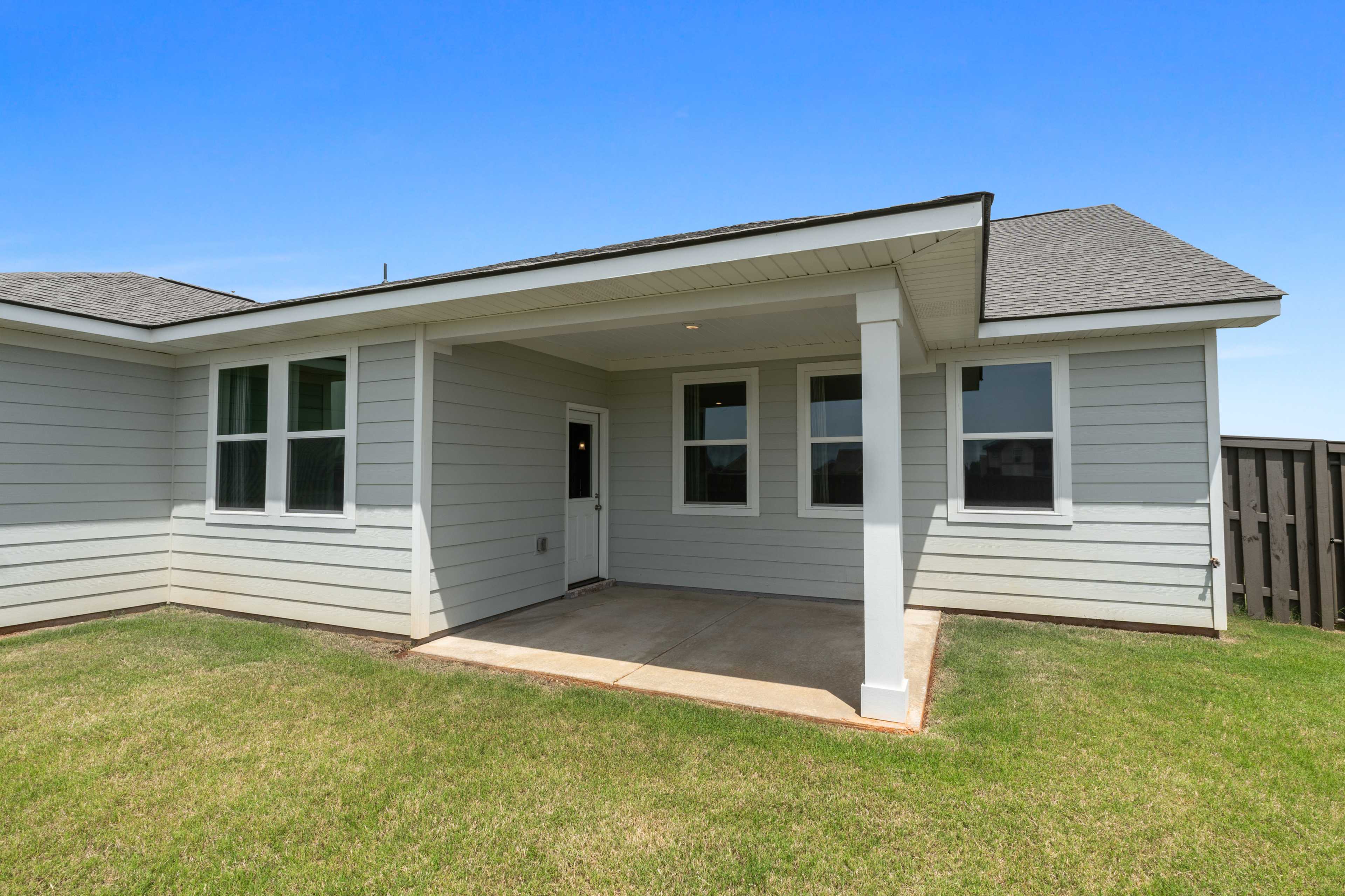 Covered patio at Anderson Farm in Athens Alabama with gray house exterior, large windows, and lush grassy yard