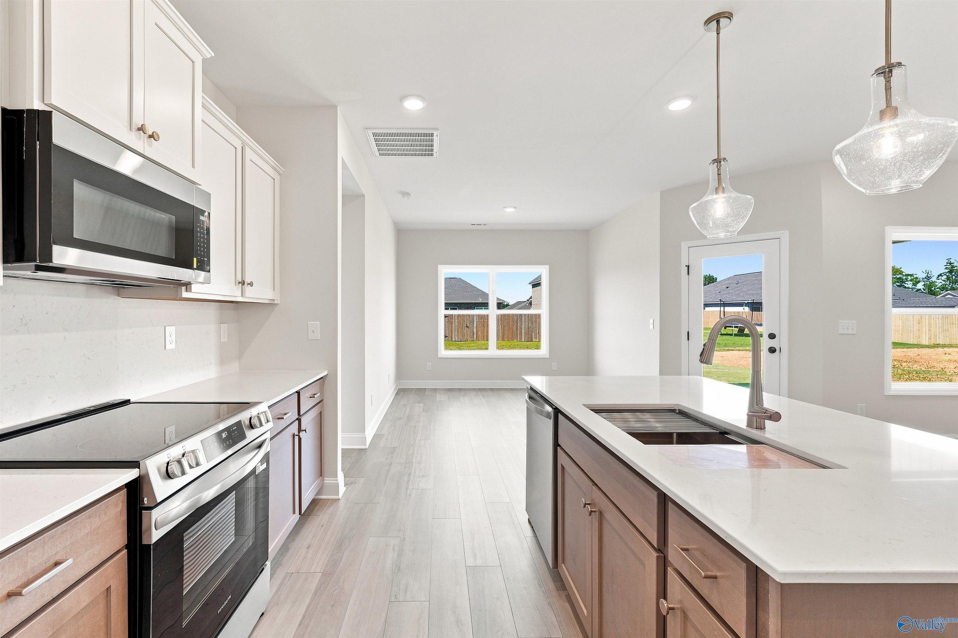Modern kitchen with white cabinetry, stainless appliances, and island sink in Davidson Homes The Everett B plan, Toney, Alabama