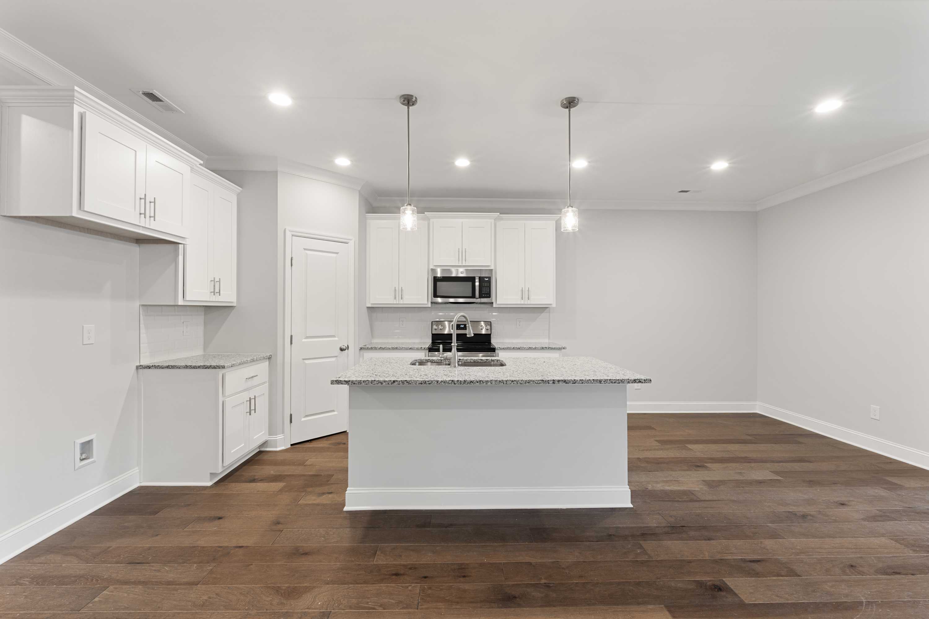 Bright kitchen in The Copeland B featuring white shaker cabinets, large center island, stainless appliances, and hardwood floors
