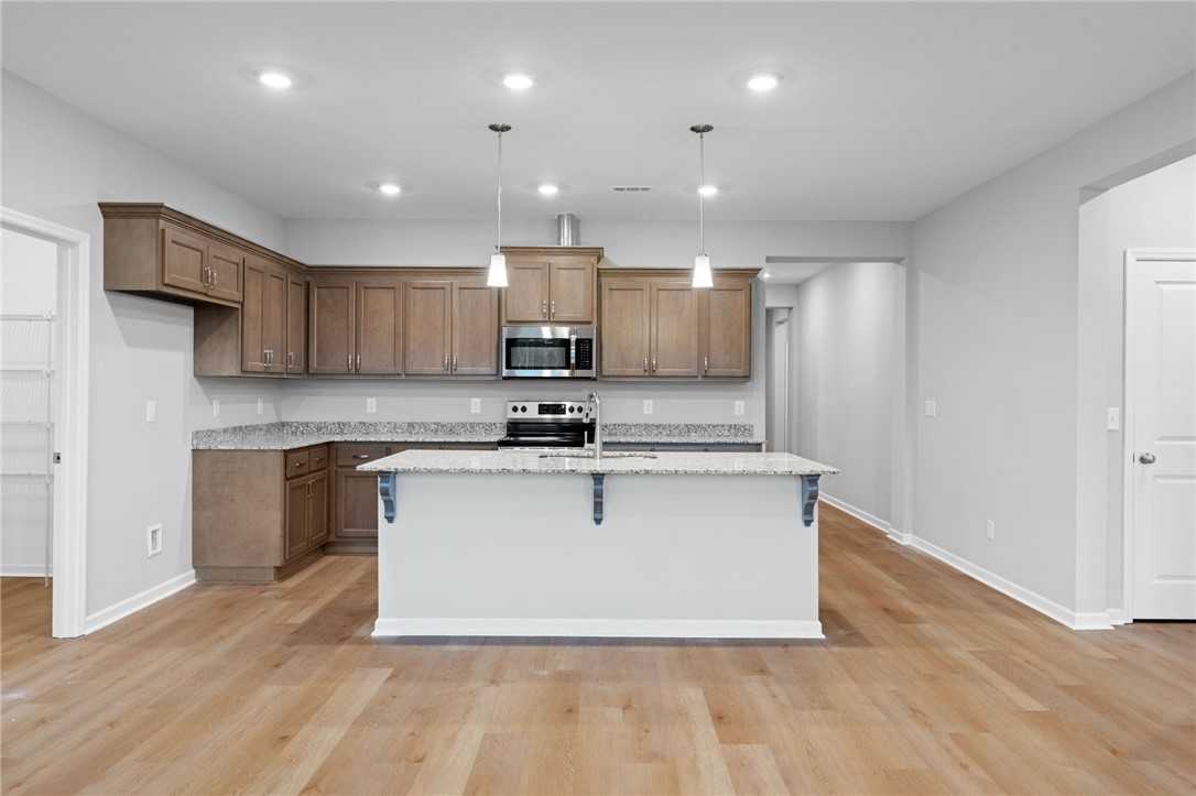 Spacious open-concept kitchen with taupe shaker cabinets, white quartz island, stainless appliances in Davidson Homes Luna B, Opelika AL