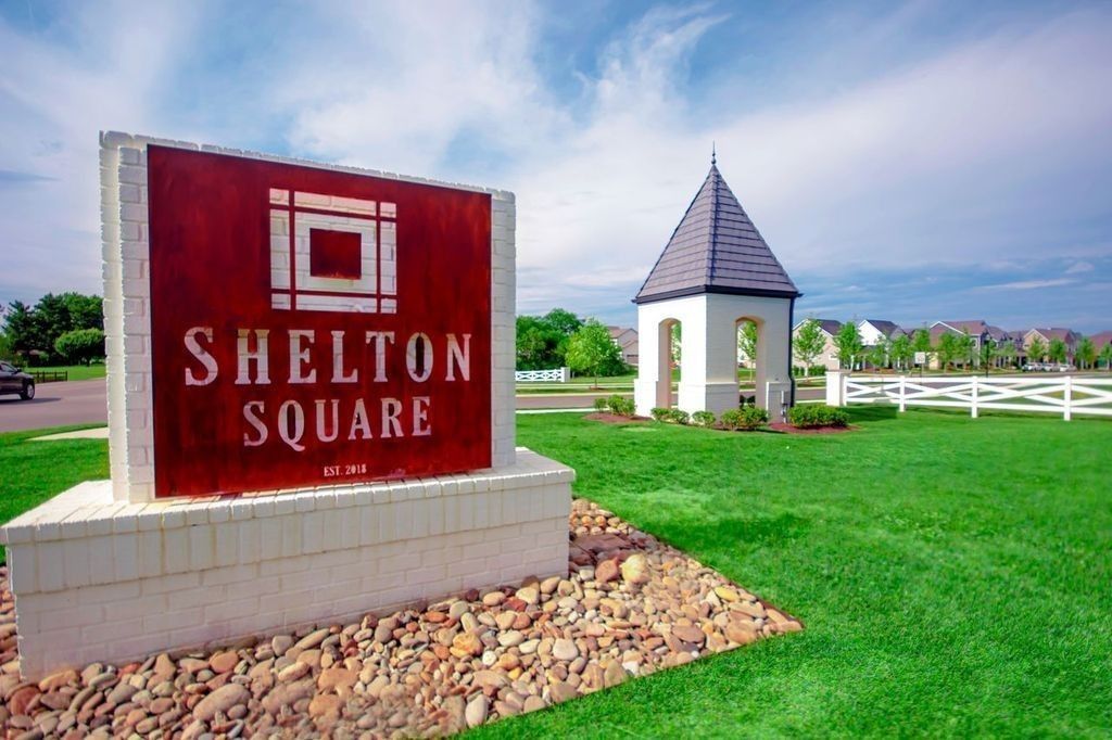 Shelton Square entrance sign with red logo, peaked-roof pavilion, white fence, and green lawn in Murfreesboro, TN