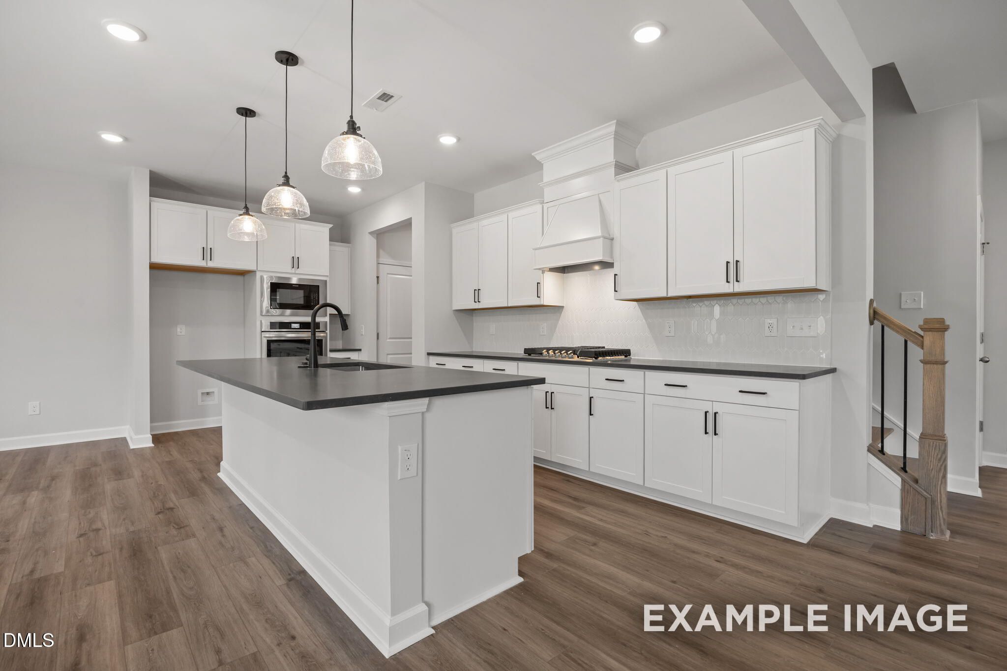 White kitchen with island, pendant lights, and stainless appliances in Davidson Homes The Beech at Wendell Ridge, NC