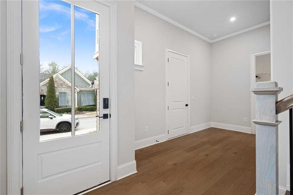 Bright foyer with hardwood floors, white trim, and glass front door overlooking Woodstock neighborhood in Davidson Homes Seaside B