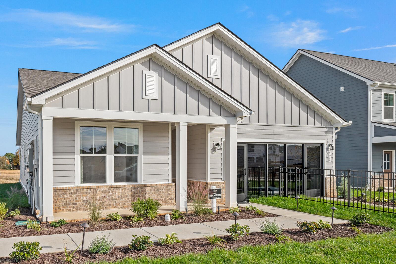 Modern gray board-and-batten home exterior at Sage Farms in White House, Tennessee with covered front porch and brick accents