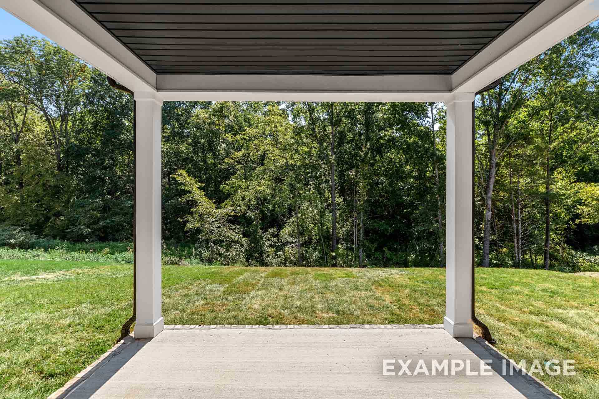 Spacious covered porch of The Henry B home design overlooking lush green lawn and wooded backyard in Mt. Juliet