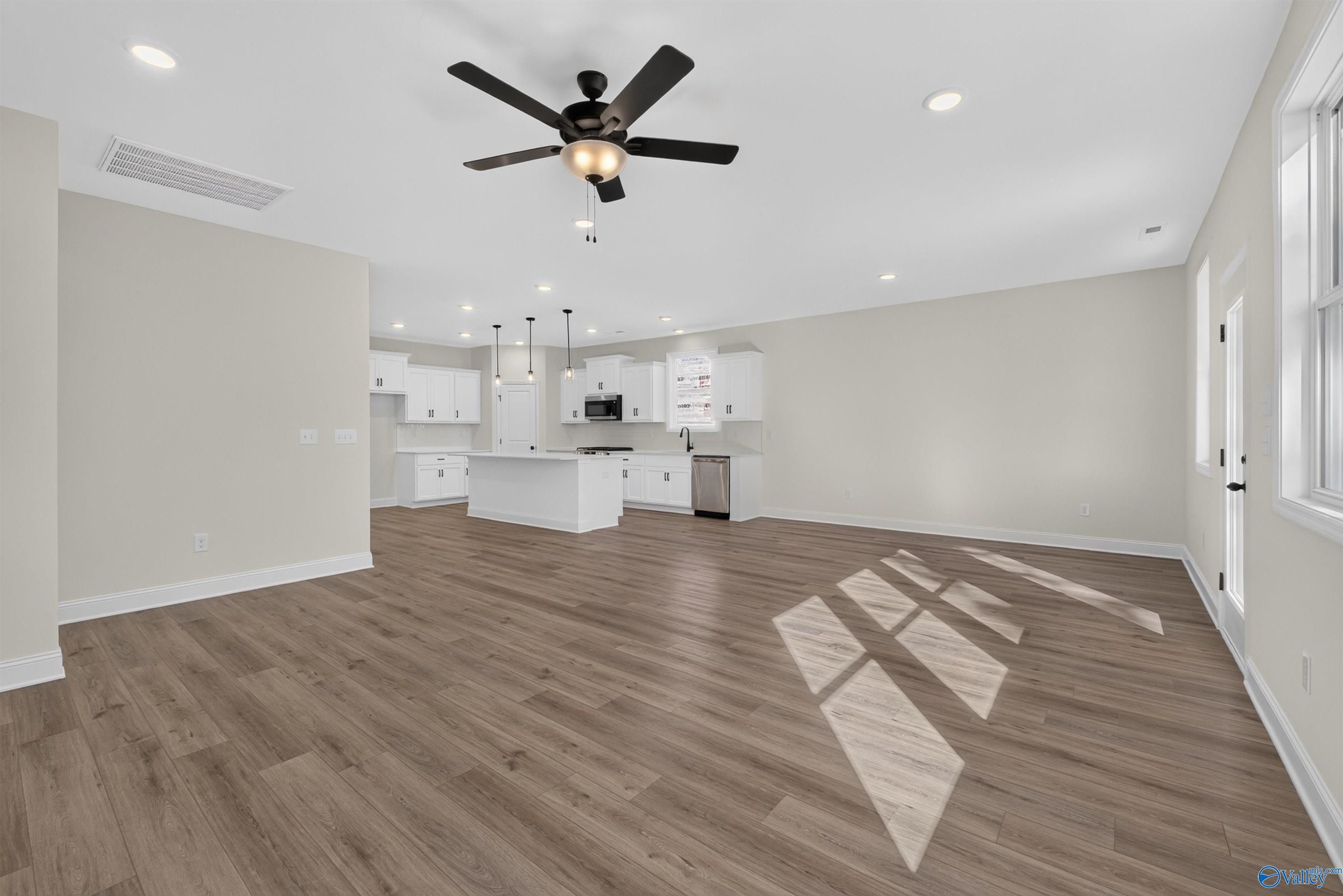Open-concept living area with luxury vinyl plank flooring and white kitchen island in Davidson Homes Ashport L, New Market AL