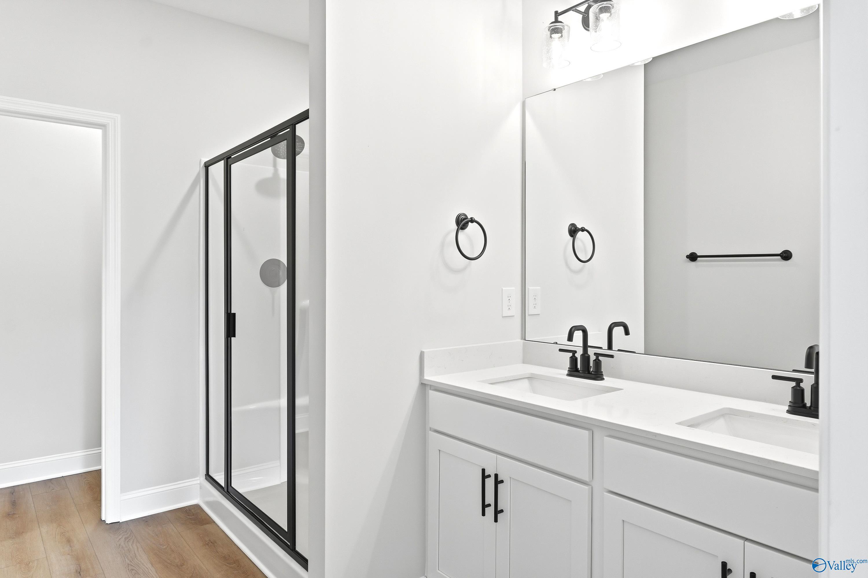 Modern bathroom with dual vanity, white cabinets, and walk-in glass shower in The Daphne C, Flint Meadows, New Market.