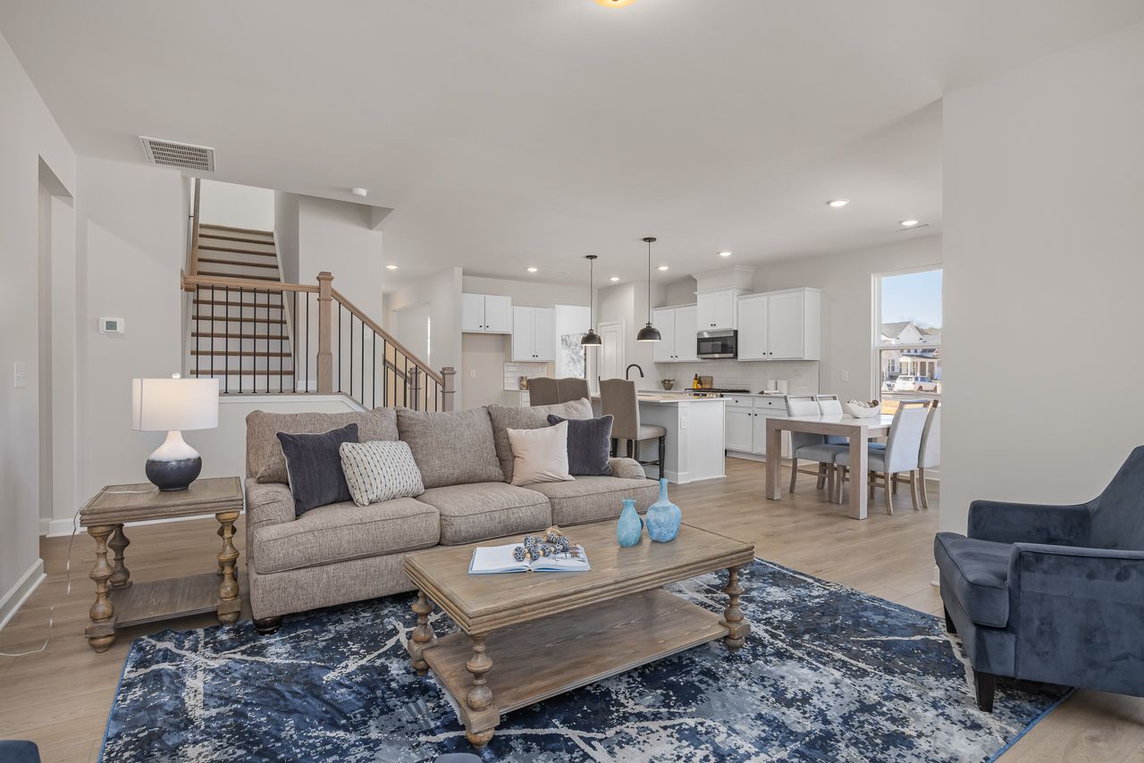 Open-concept living room at Retreat at North Main in Lillington, NC with kitchen, dining area, and modern decor.